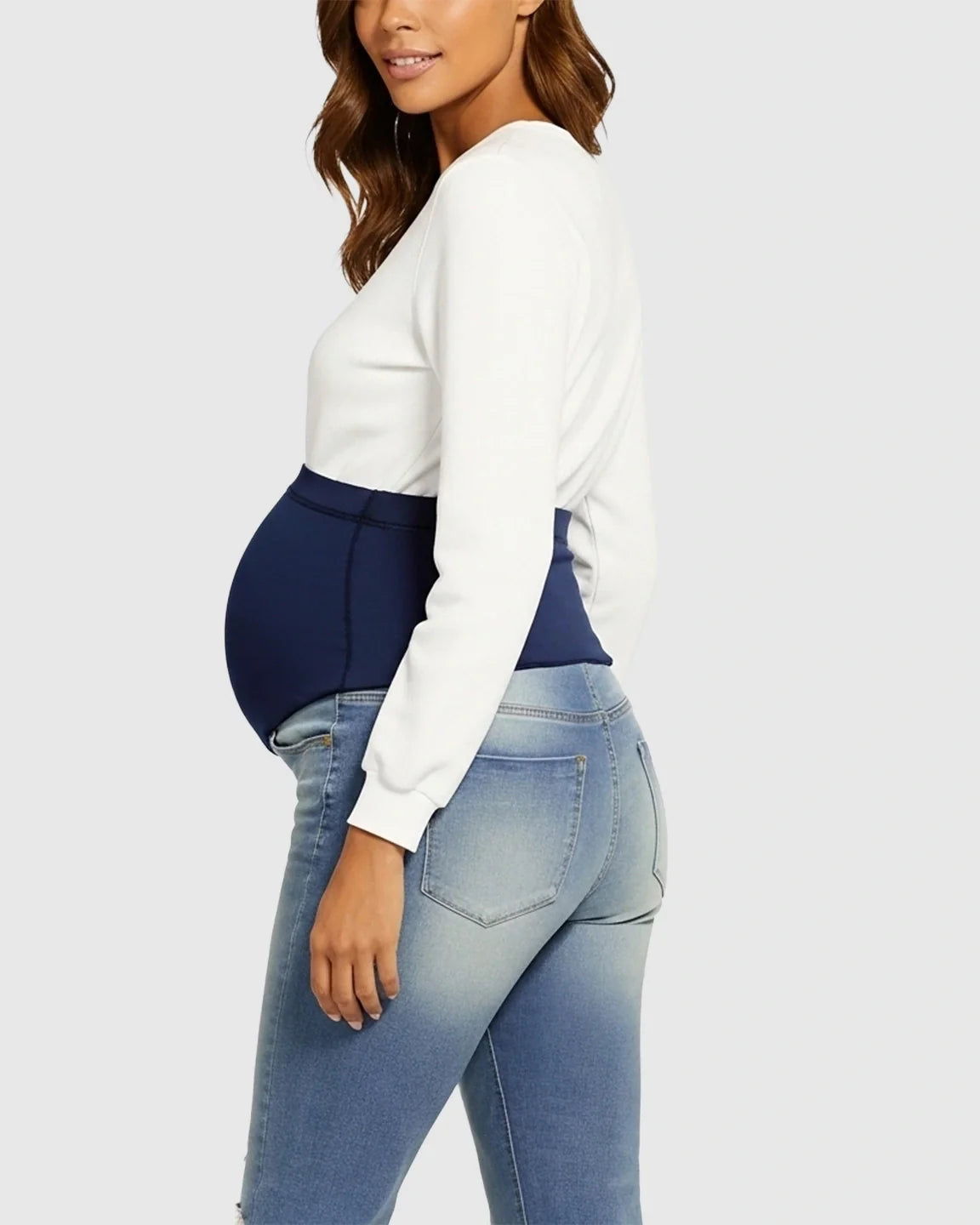 Pregnant woman in light wash maternity jeans with a navy high-waist belly support band.