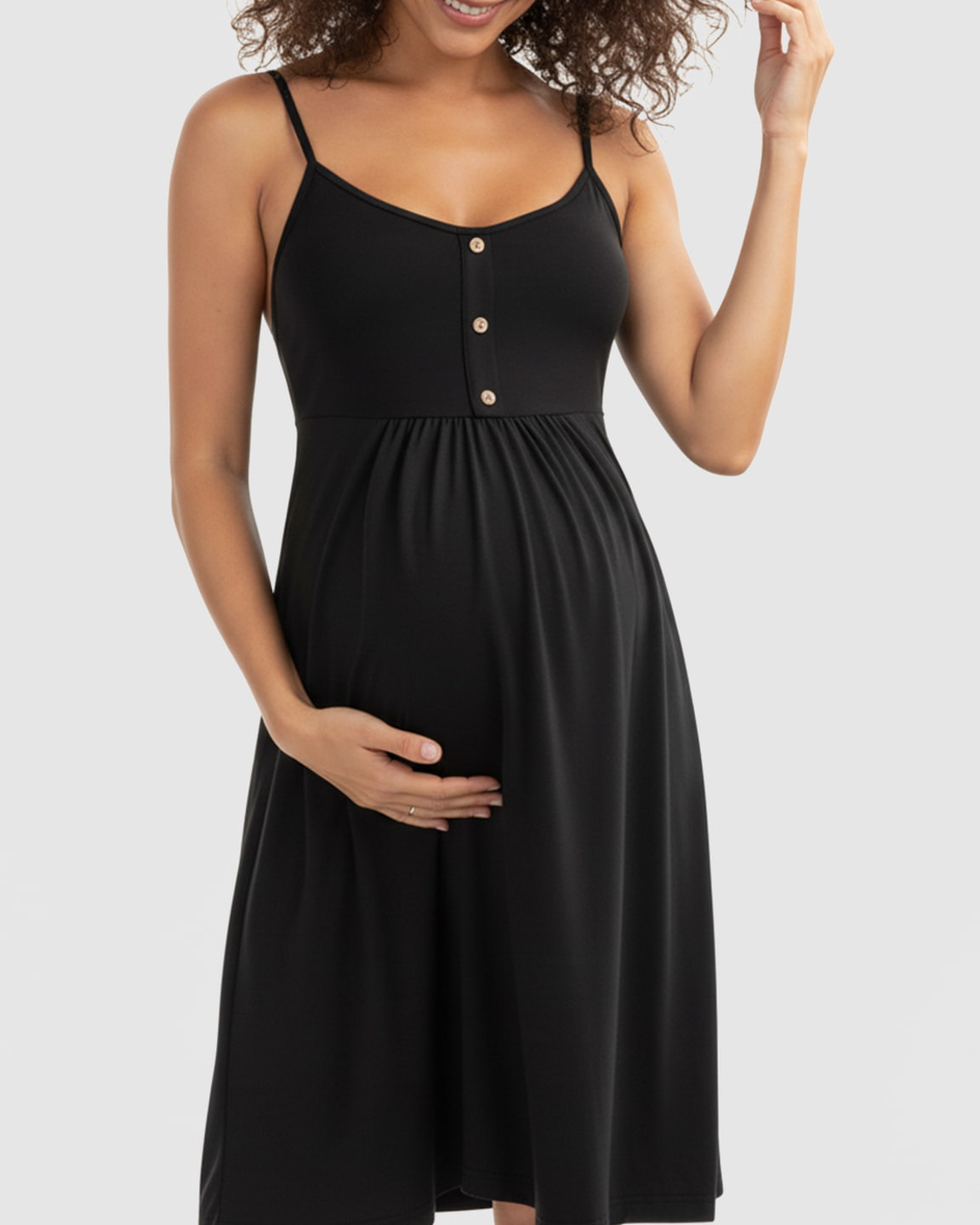 Black thin-strap A-line maternity midi dress with wooden buttons, worn by a pregnant woman.