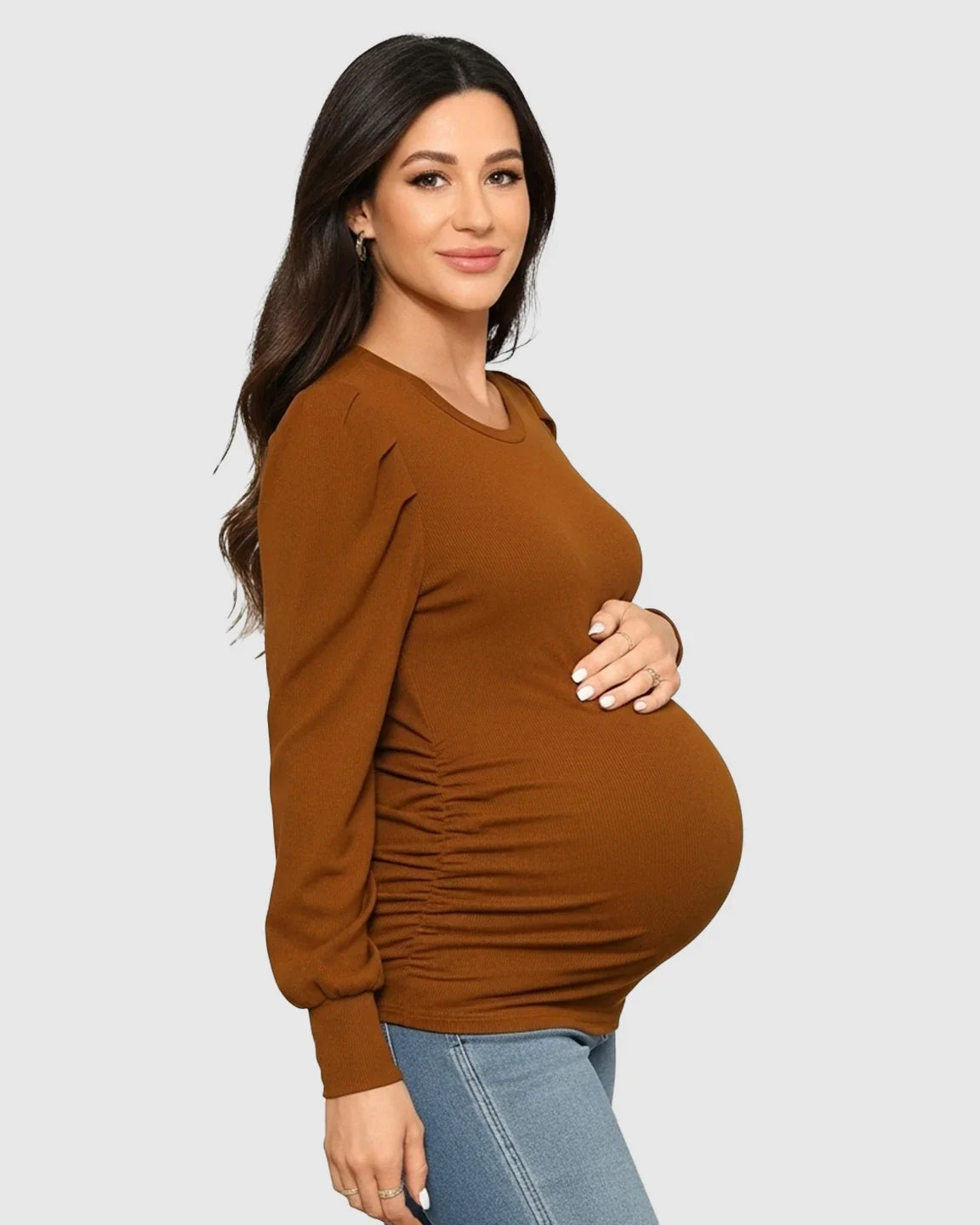 Pregnant woman in a warm brown, long-sleeve ruched maternity top with a round neck and side pleats.