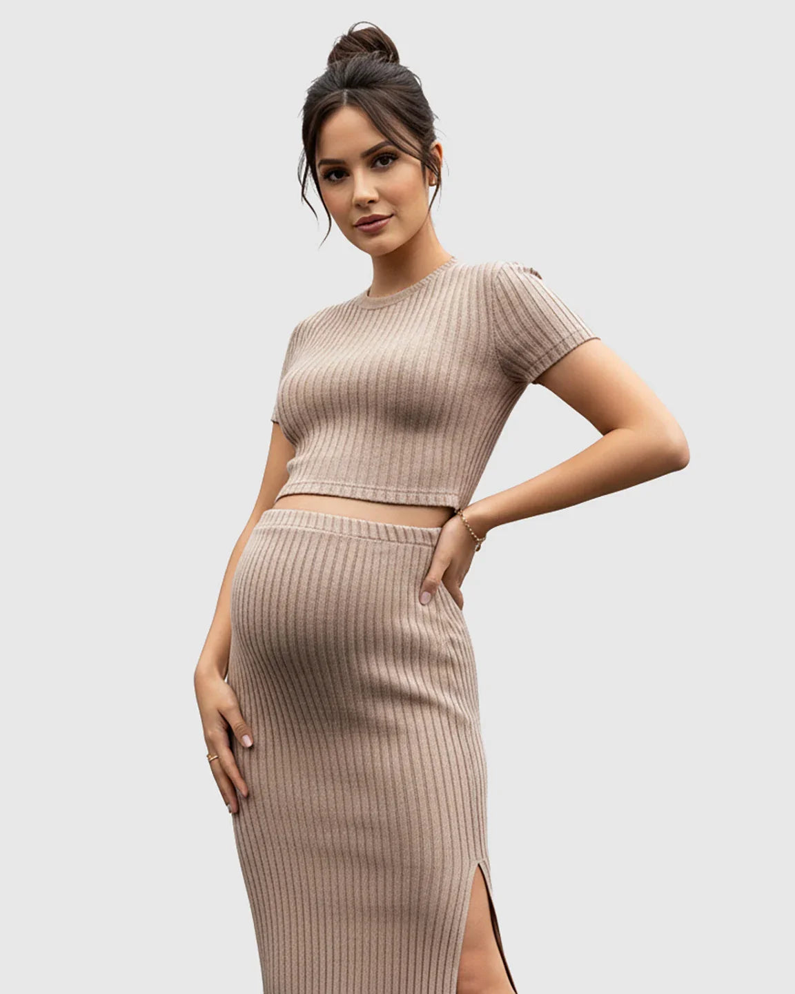 Pregnant woman in a beige ribbed crop top and side-slit bodycon maternity skirt set.
