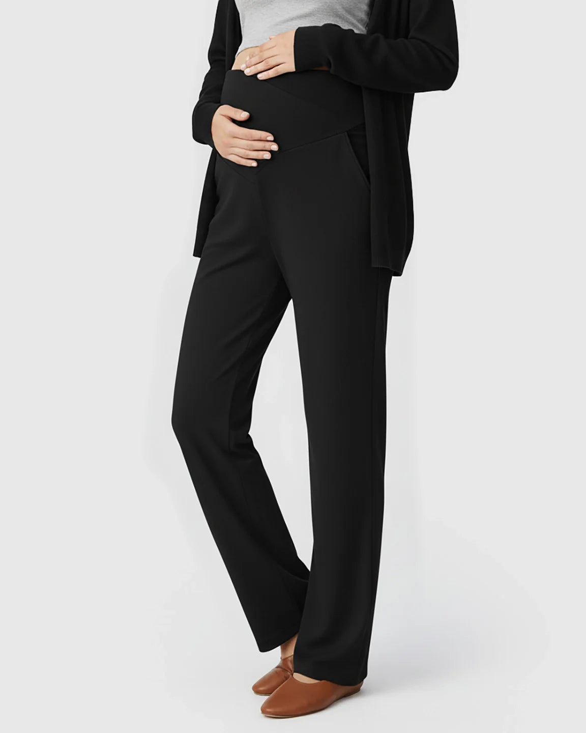 Pregnant woman in black crossover waist wide-leg maternity lounge pants with side pockets and brown flats.