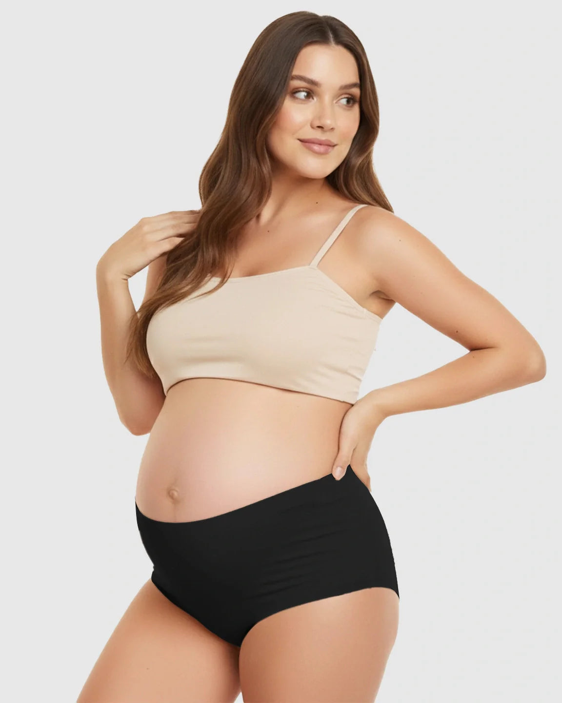 Pregnant woman modeling black seamless high-waist support maternity underwear and a nude bra.
