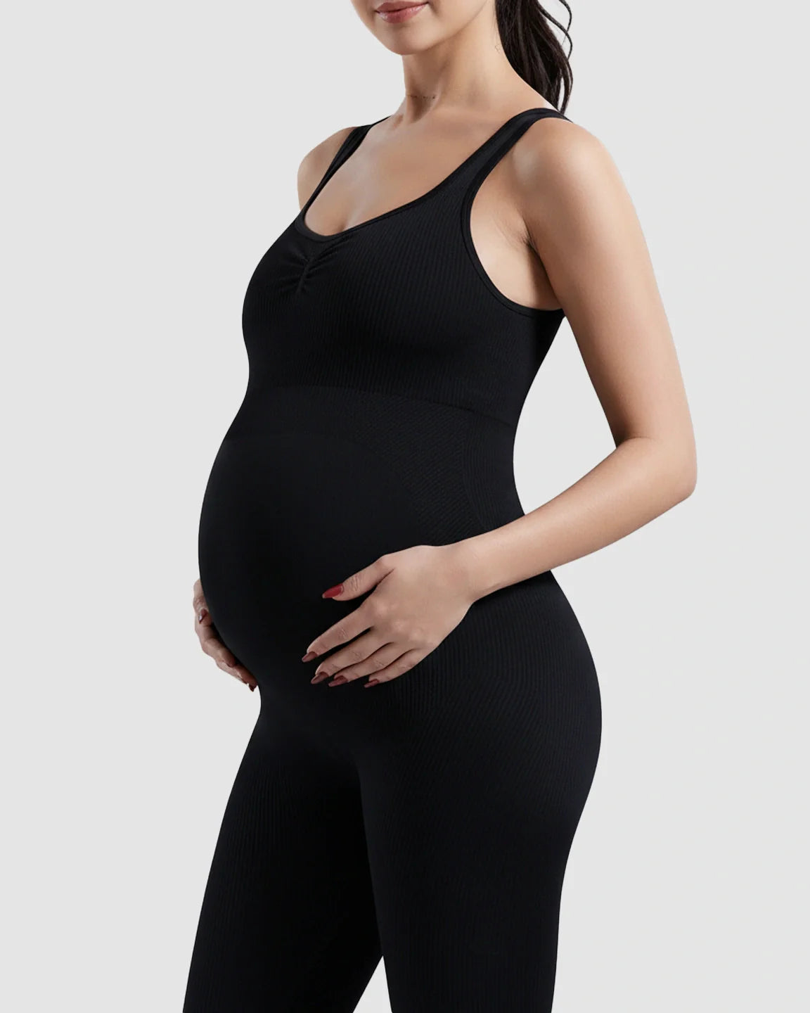 Black ribbed high-waisted stretch maternity bodysuit on a pregnant woman, designed for comfort and support.