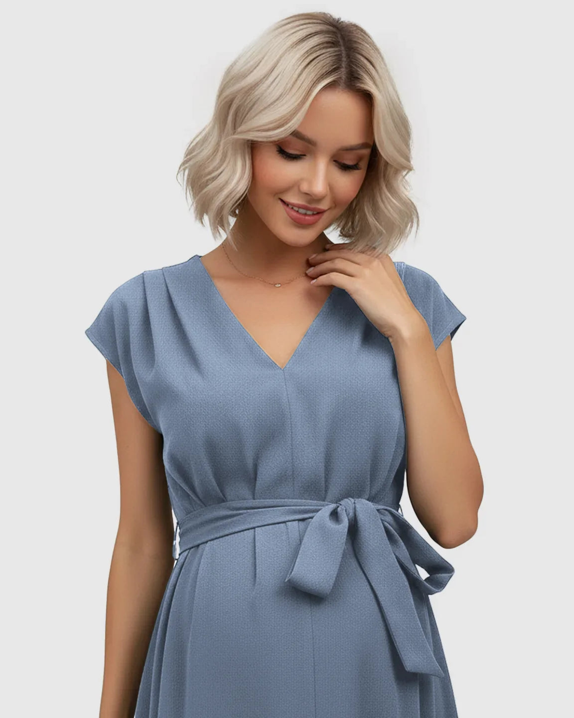 Blonde woman in a blue V-neck maternity midi dress with flutter sleeves and an adjustable tie-waist.