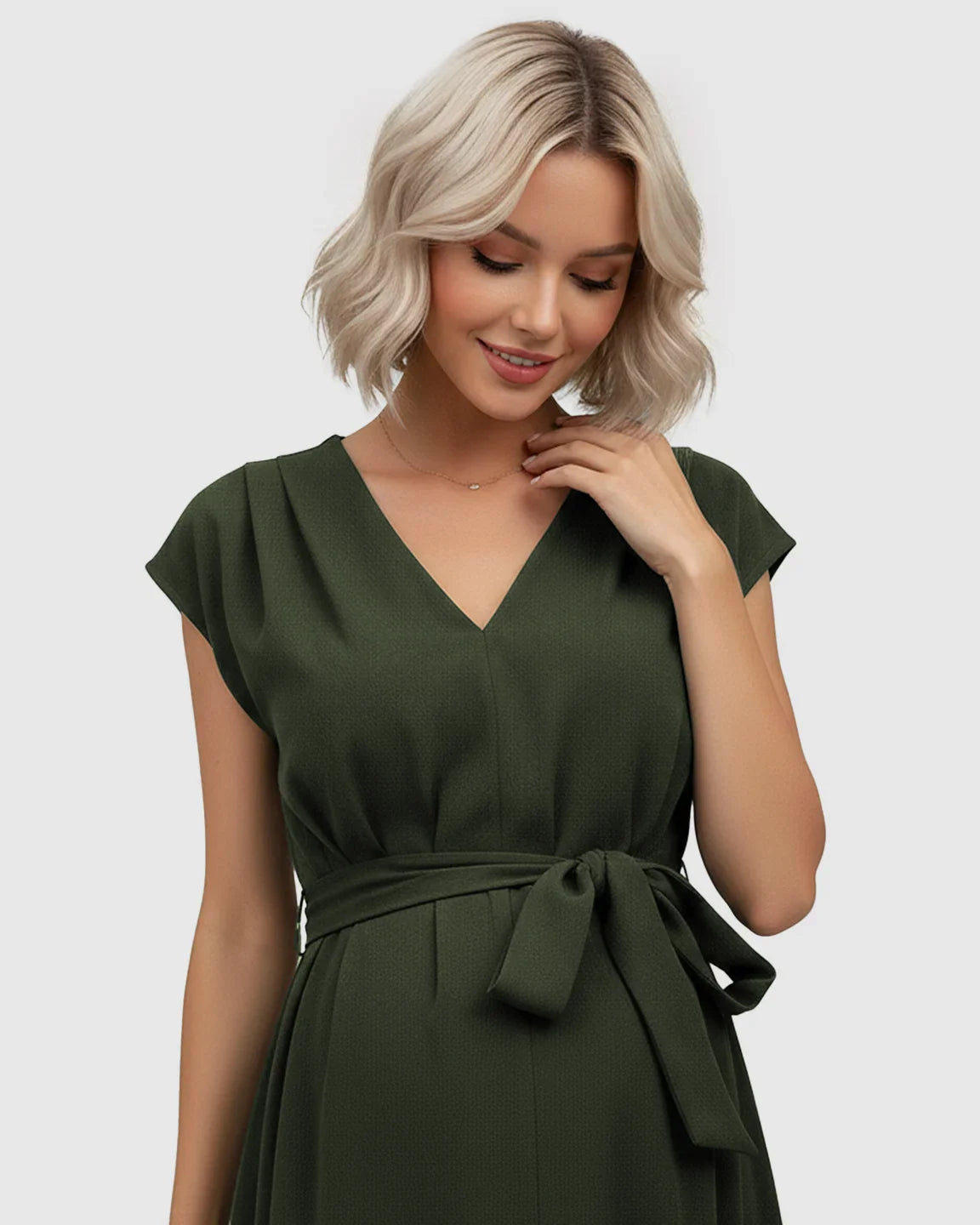 Blonde model wearing a dark green V-neck maternity midi dress with flutter sleeves and an adjustable tie-waist.