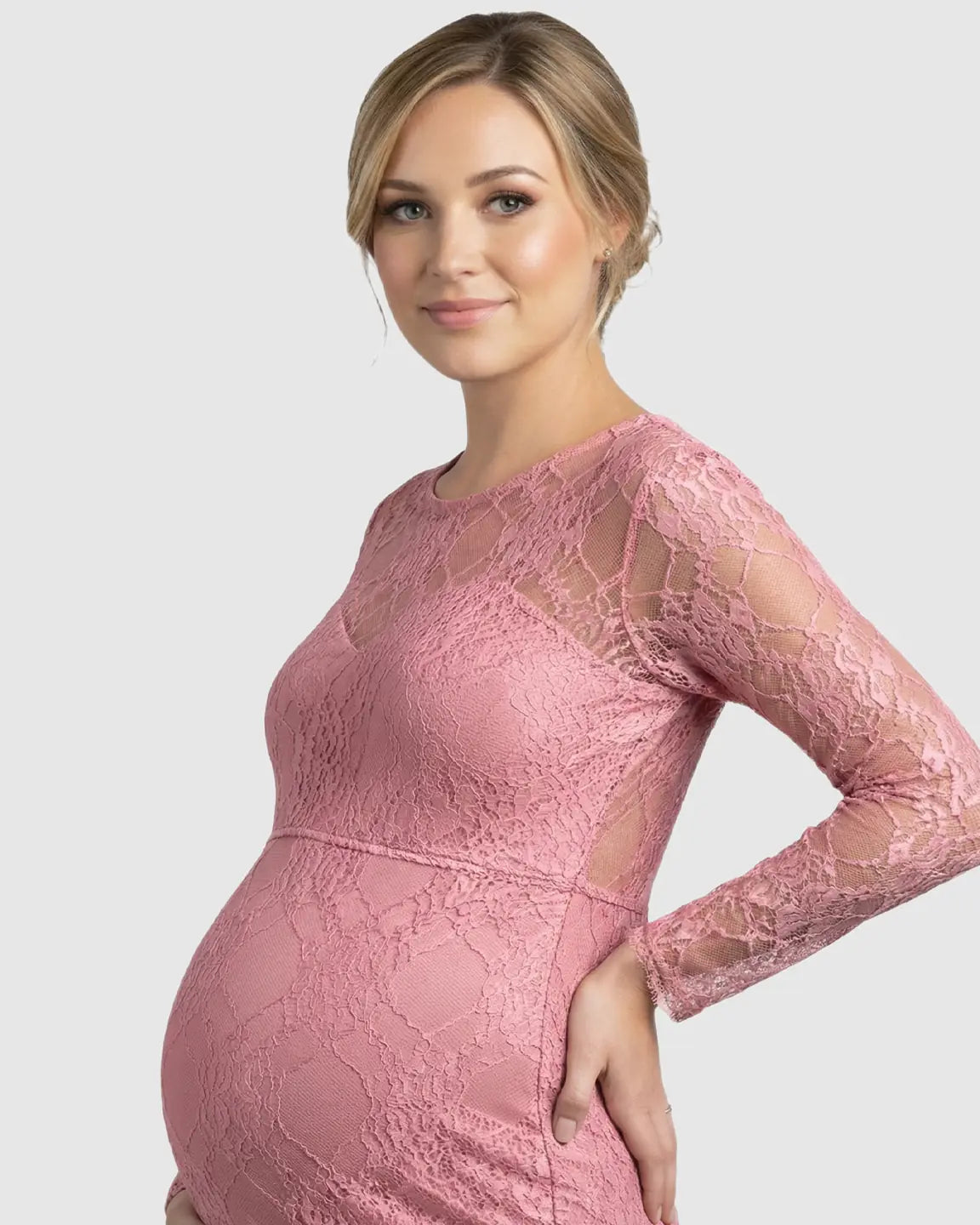 Pregnant woman in a pink sheer lace trumpet maternity gown with long sleeves and a classic neckline.