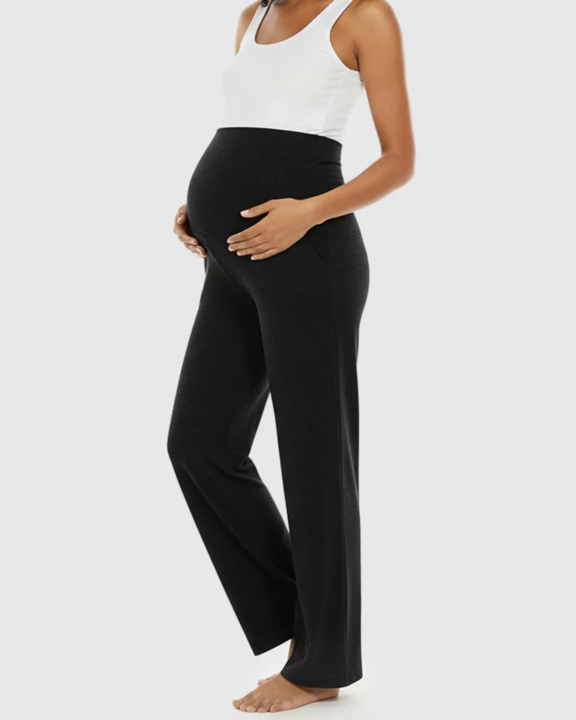 Pregnant woman in black wide-leg maternity lounge pants with a foldable waistband and side pockets.