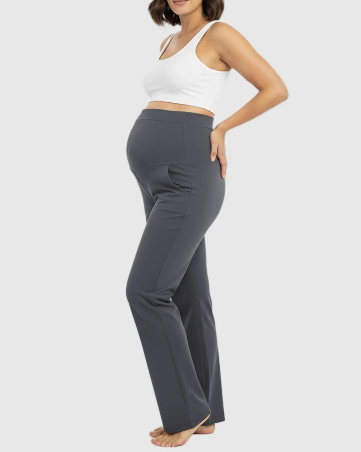 Pregnant woman in charcoal gray stretch flared maternity pants with over-belly waistband and pockets.