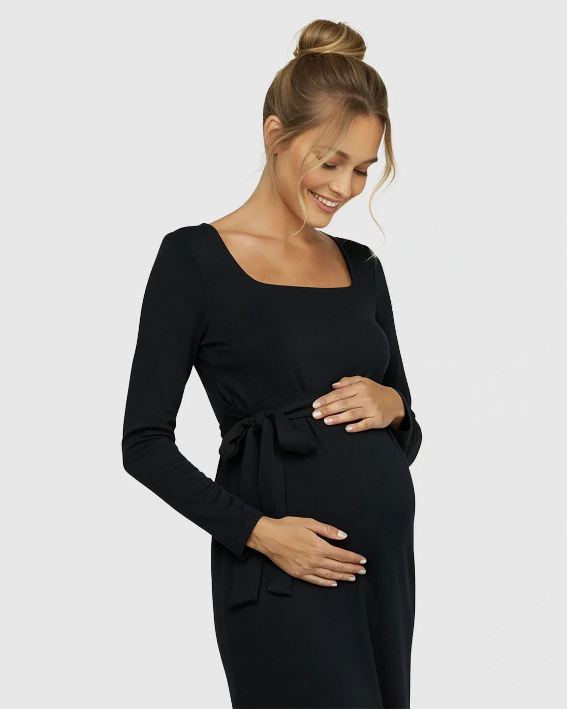 Smiling pregnant woman in a black square neck, long-sleeve, side-tie bodycon maternity midi dress.
