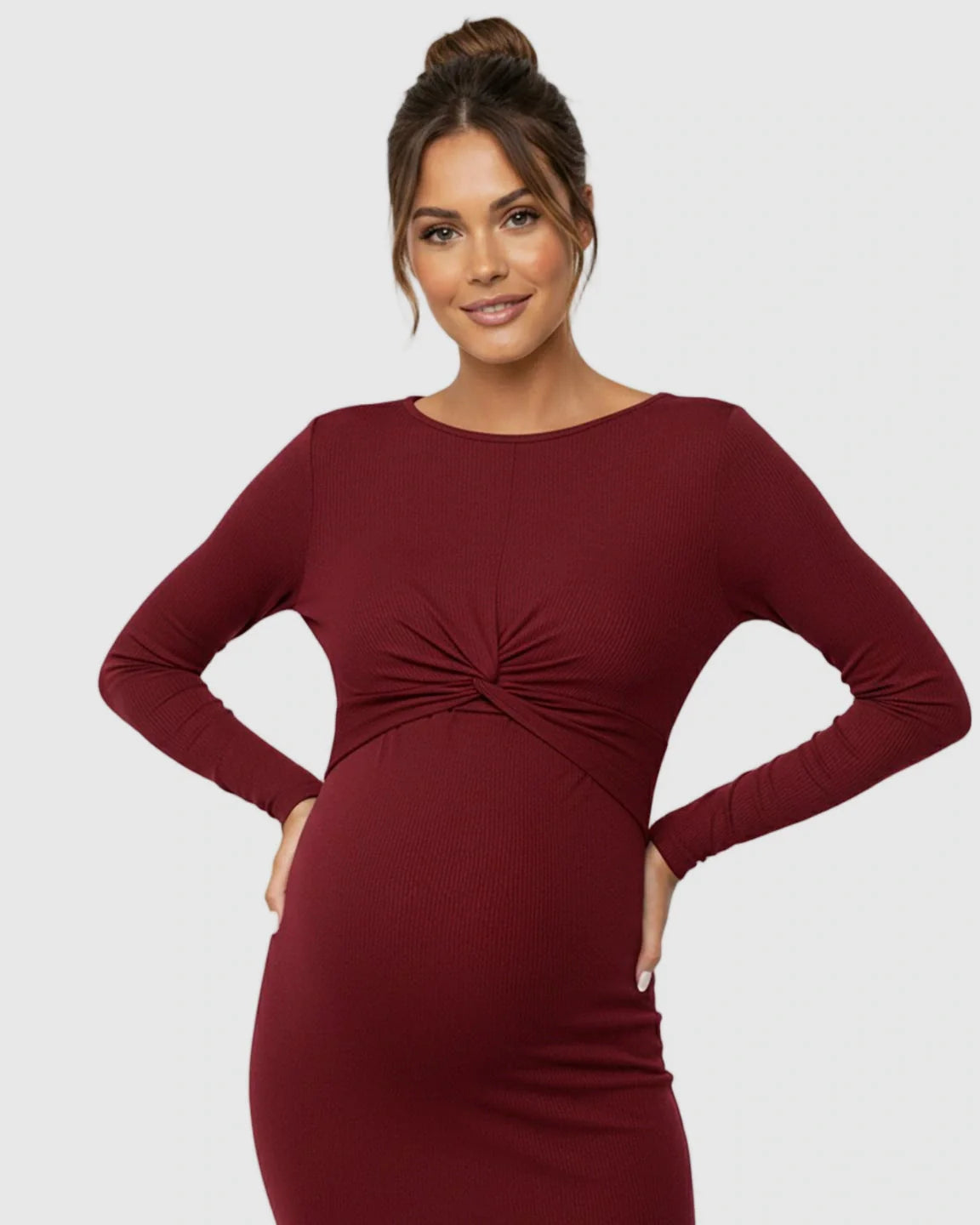 Smiling pregnant woman in a long-sleeve, red ribbed bodycon maternity dress with a twist-front empire waist.
