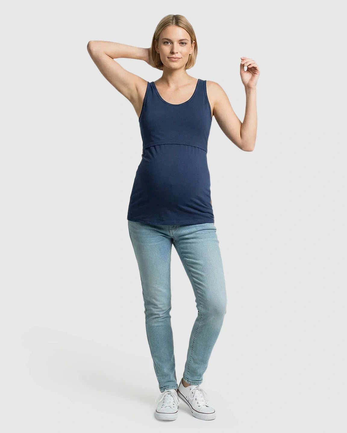 Woman in a navy stretch nursing-access maternity tank top and light wash jeans.