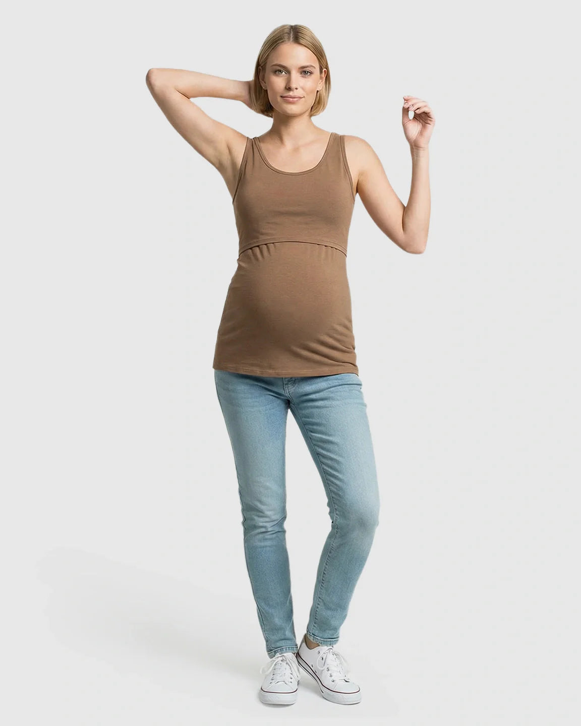 Woman in a brown stretch nursing-access maternity tank top and light blue jeans.