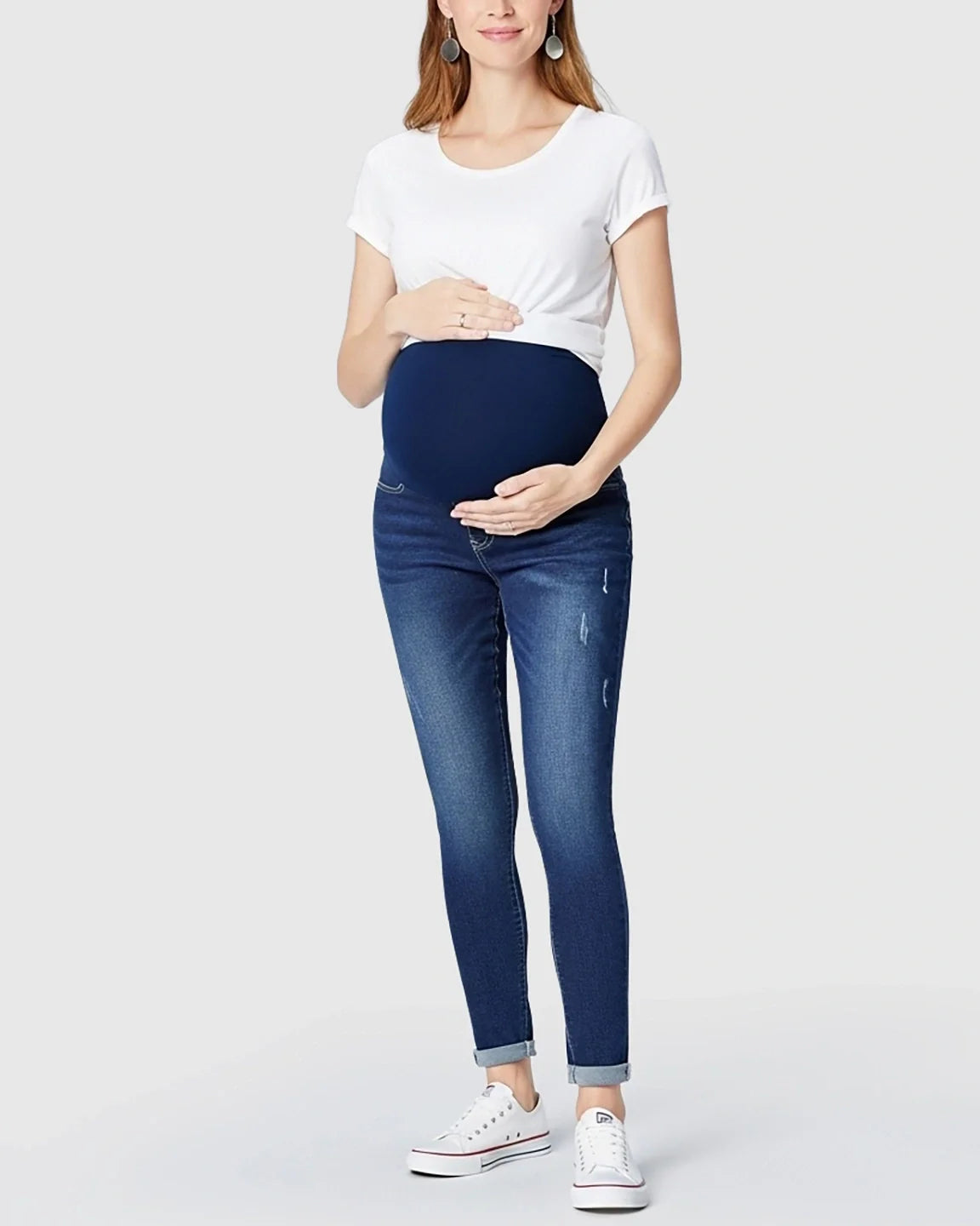 Woman wearing dark wash full panel distressed maternity skinny jeans with a white t-shirt.