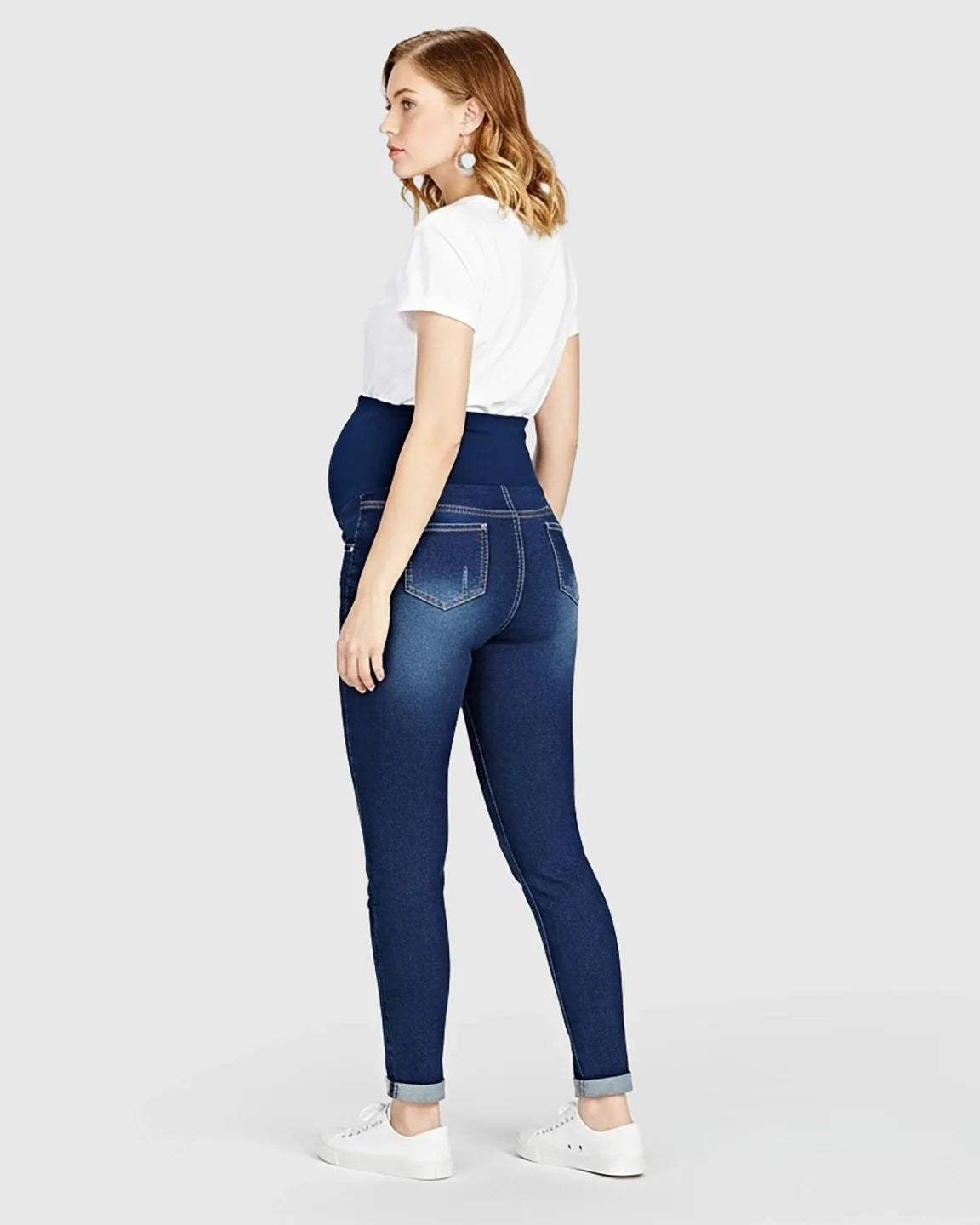 Woman in dark wash distressed maternity skinny jeans with a full panel waistband.