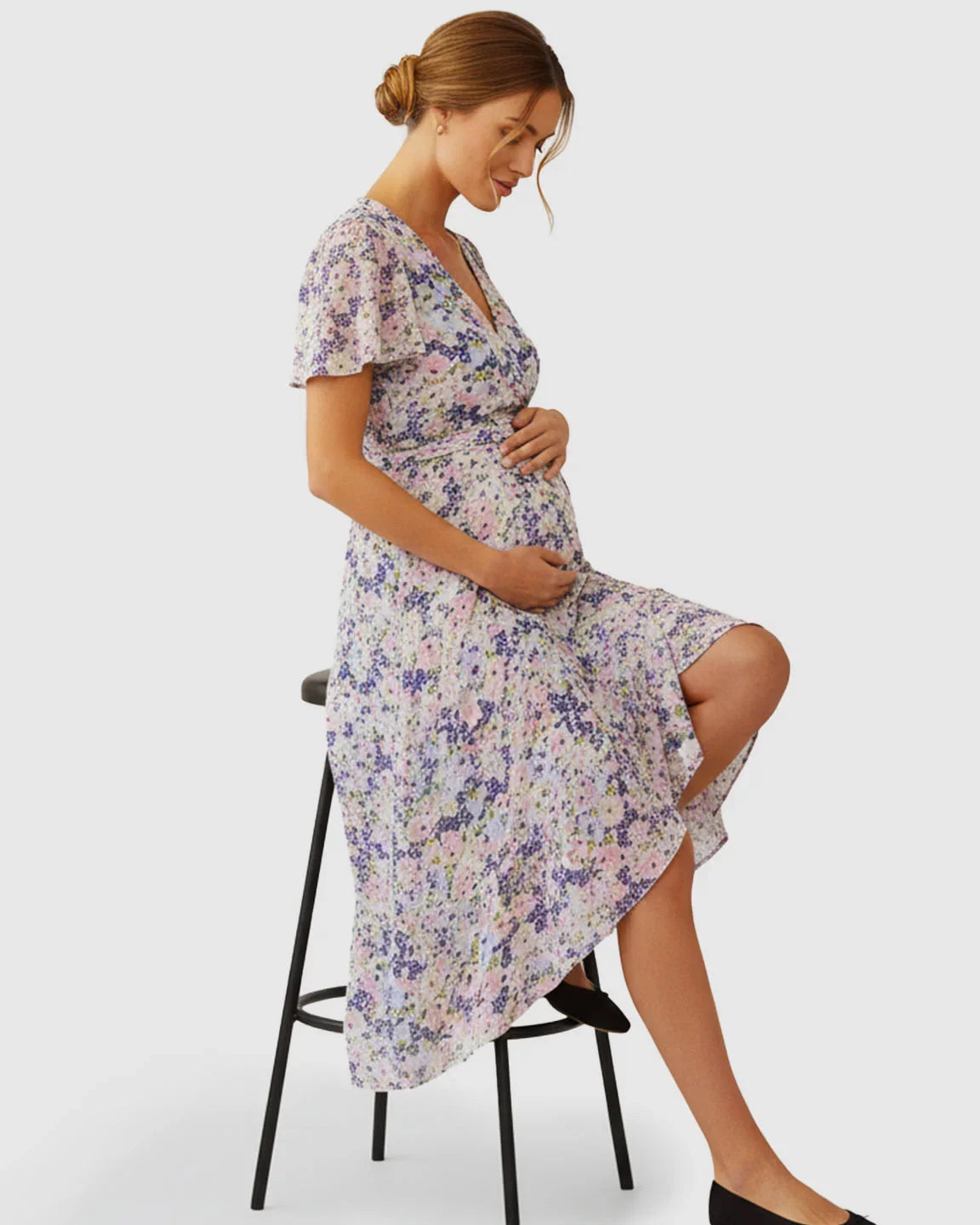 Maternity V-neck wrap-style midi dress with flutter sleeves, white with purple and pink floral print.