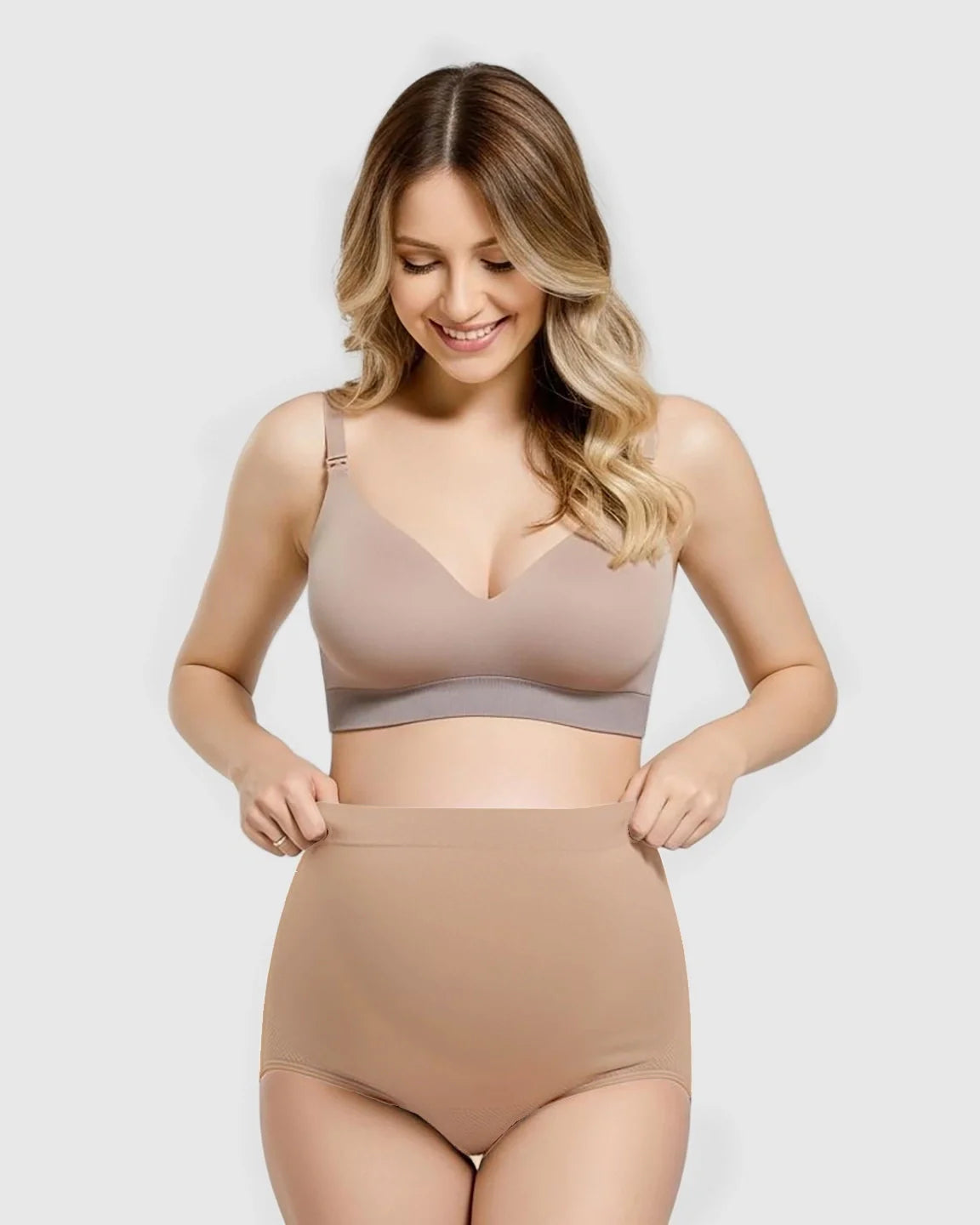 Smiling pregnant woman in a beige seamless high-waist maternity panty and matching bra.