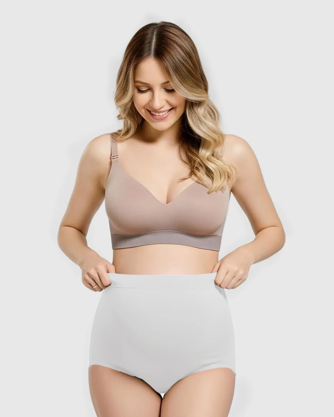 Smiling woman wearing a beige maternity bra and light grey seamless high-waist maternity panties.