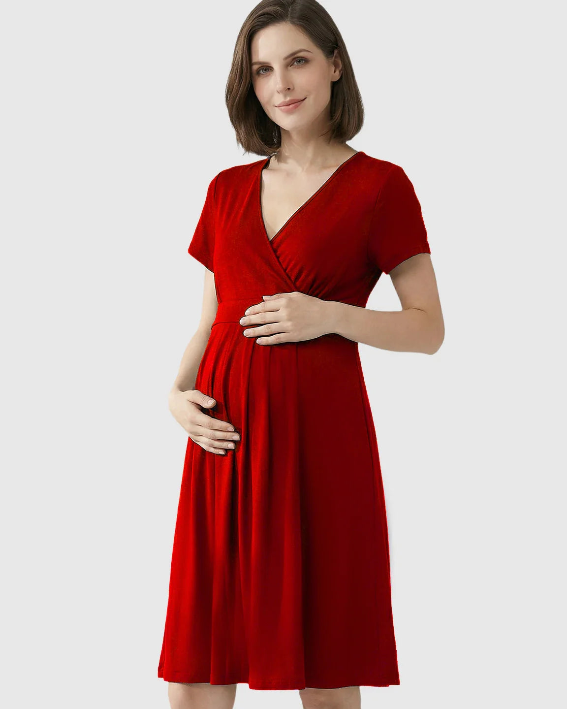 Smiling pregnant woman in a red V-neck A-line maternity and nursing dress, holding her baby bump.