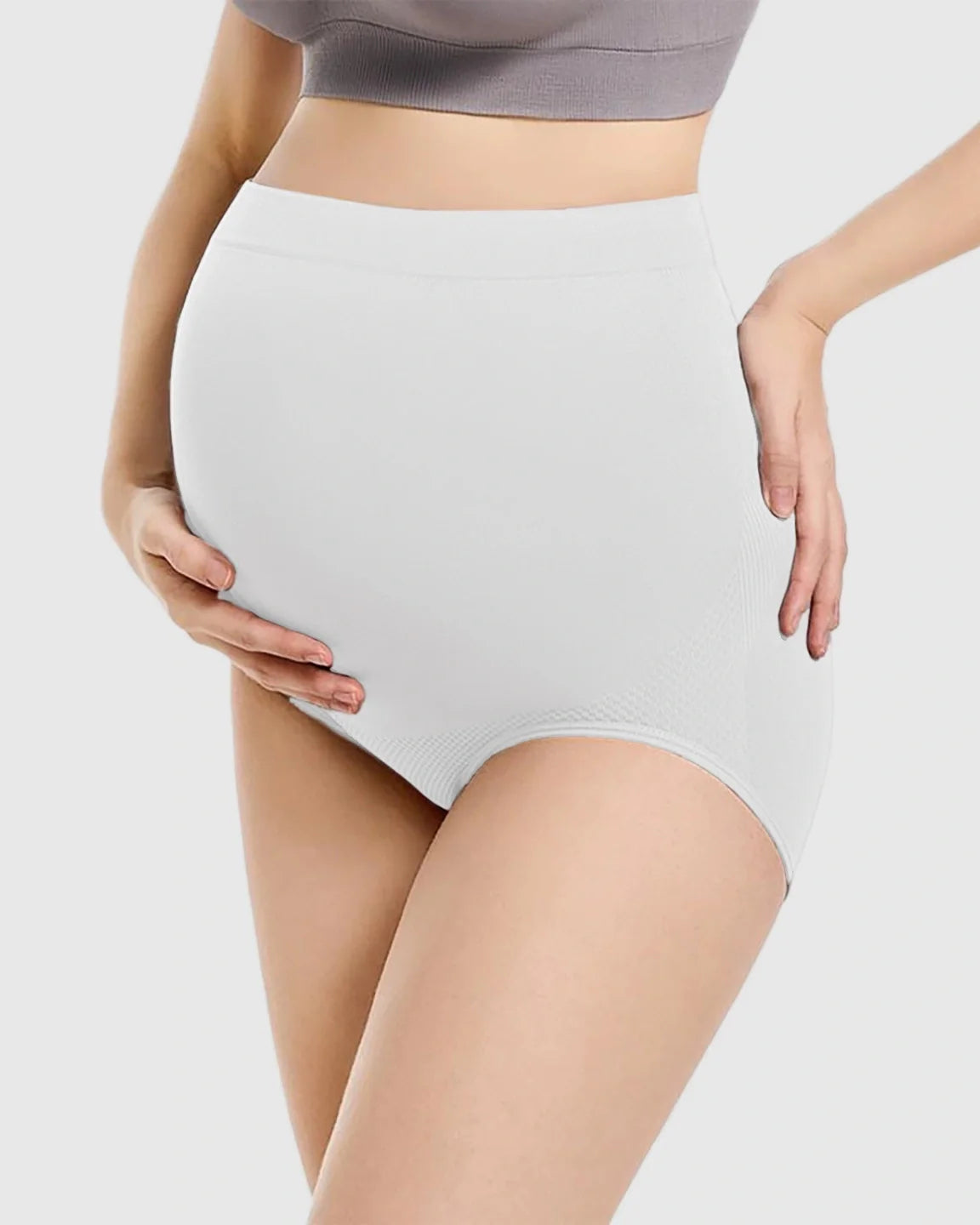 White seamless high-waist maternity panties supporting a pregnant belly, with subtle textured side panels.