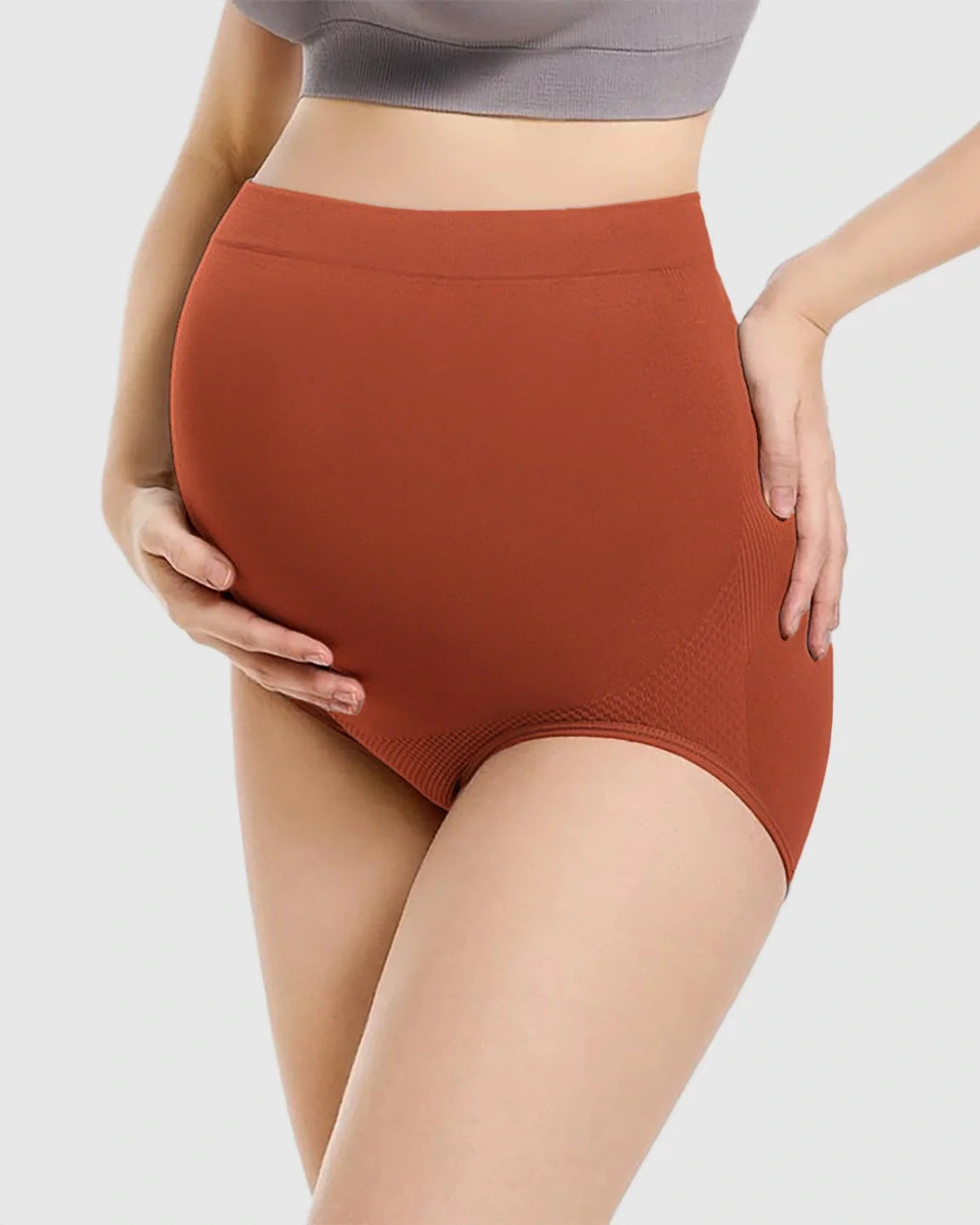 Pregnant woman wearing rust-colored, high-waist seamless maternity panties with a supportive design.
