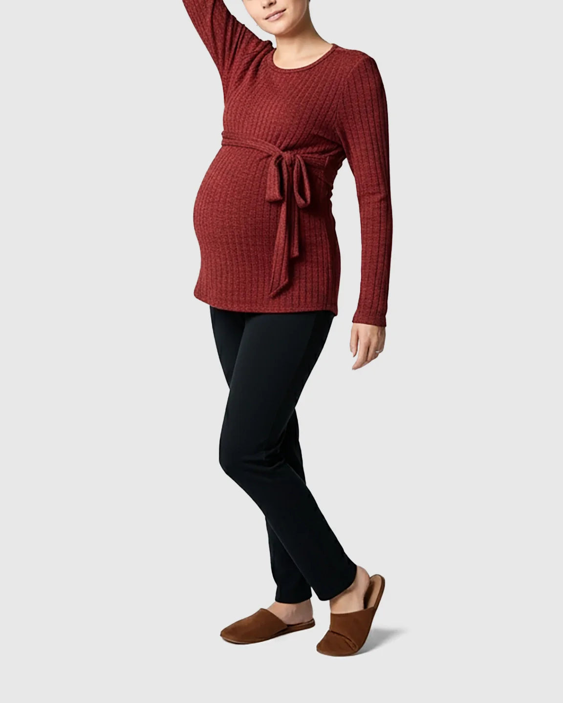 Pregnant woman in a red ribbed tie-waist long sleeve maternity sweater and black pants.