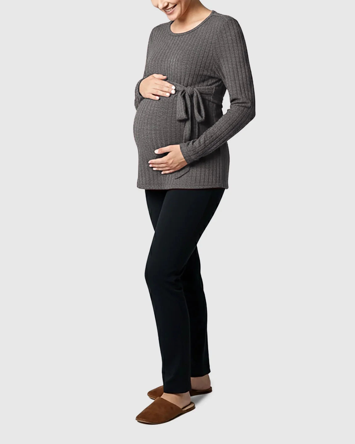 Pregnant woman in a charcoal ribbed tie-waist long sleeve maternity sweater and black pants.