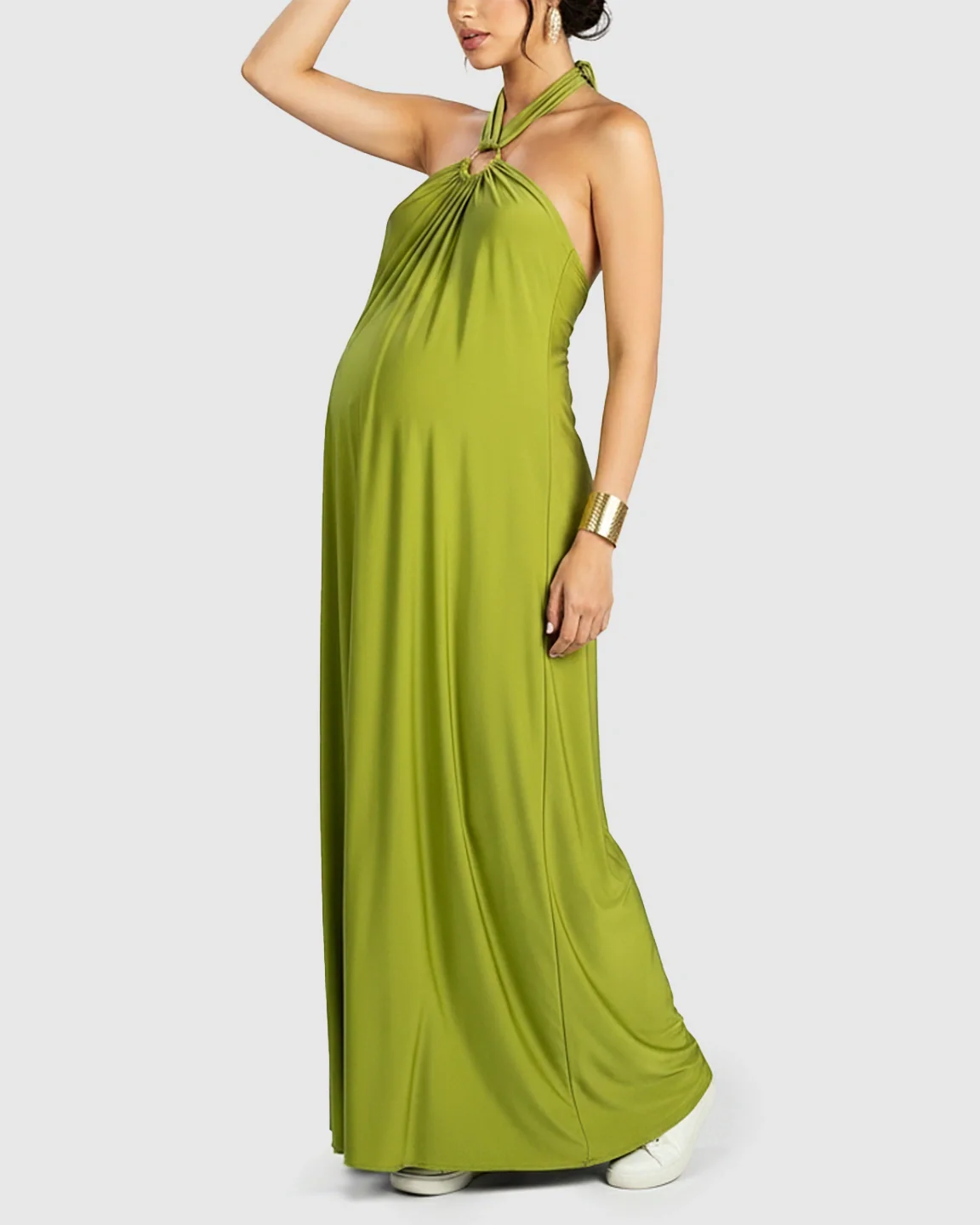 Maternity model in a flowing lime green backless halter neck maxi dress with a relaxed fit.