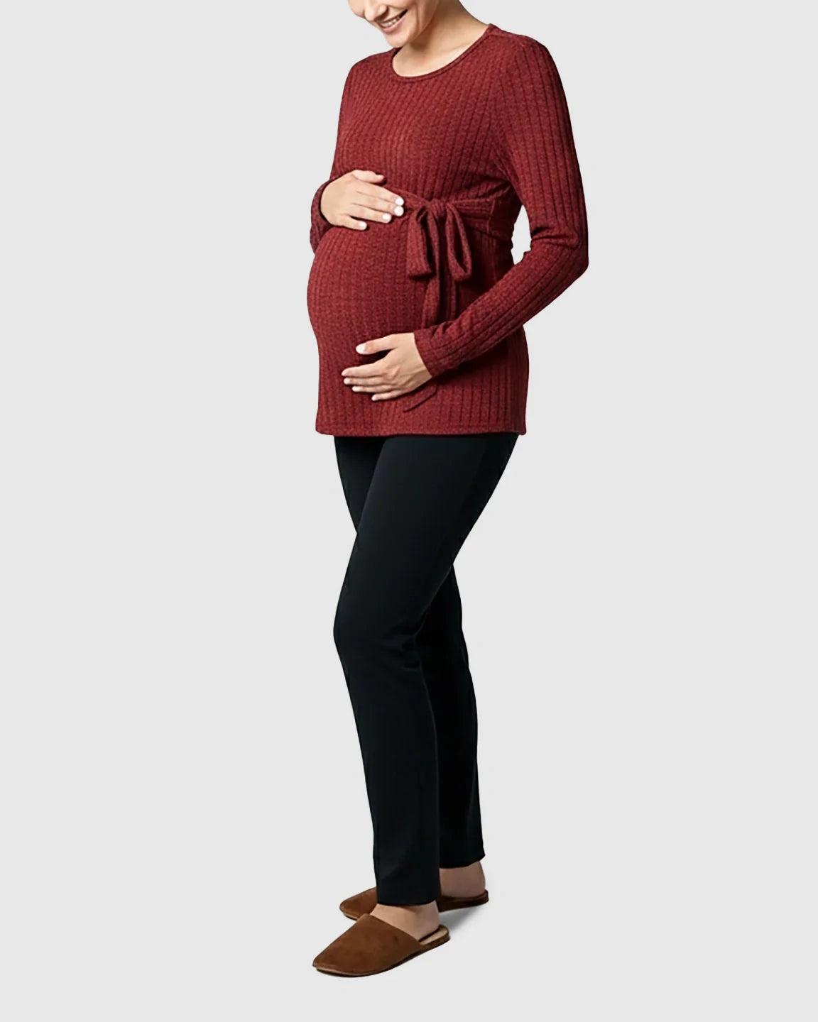 Pregnant woman in a rust ribbed tie-waist long sleeve maternity sweater and black pants.