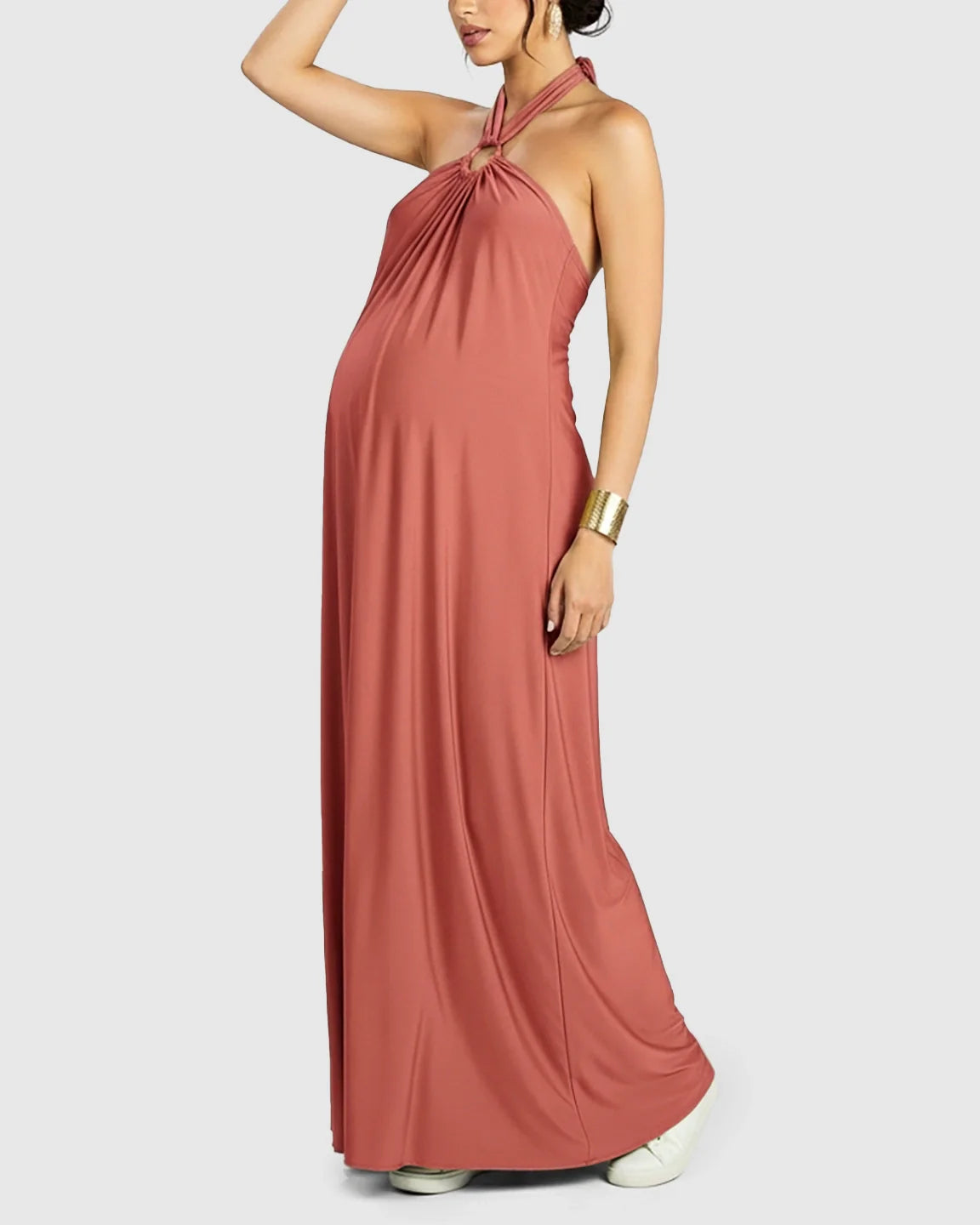 Maternity model in a terracotta backless halter neck chiffon maxi dress with a flowing skirt.