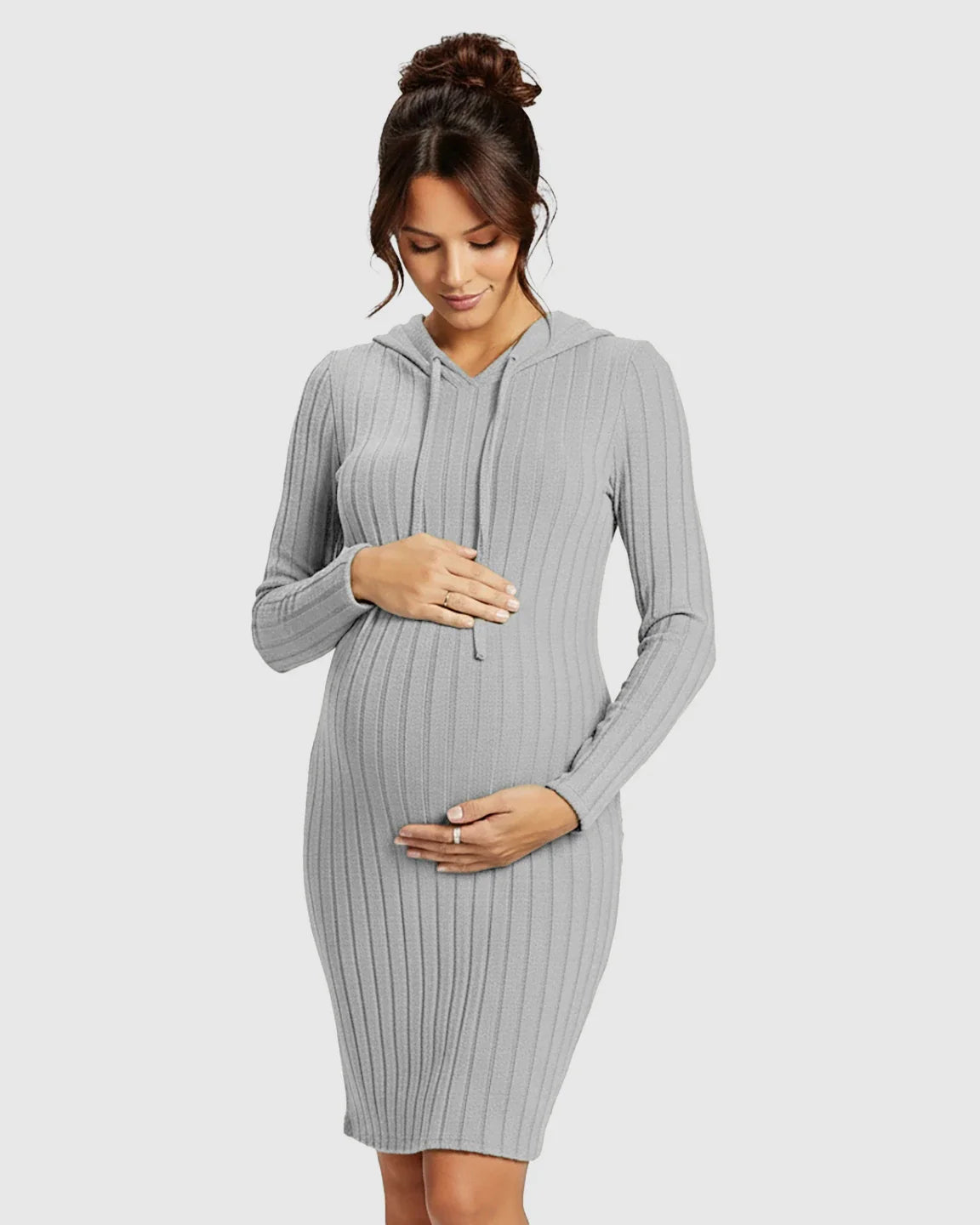 Pregnant woman in a grey ribbed bodycon hooded maternity midi dress, gently holding her bump.