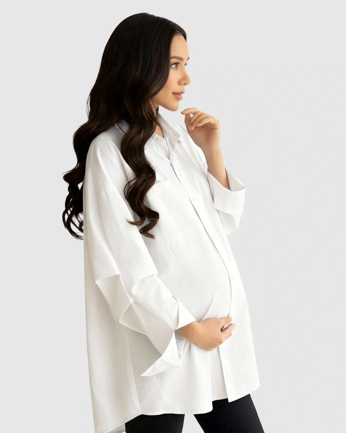 Pregnant woman in a white cotton lapel-collar button-front maternity tunic, styled over black leggings.