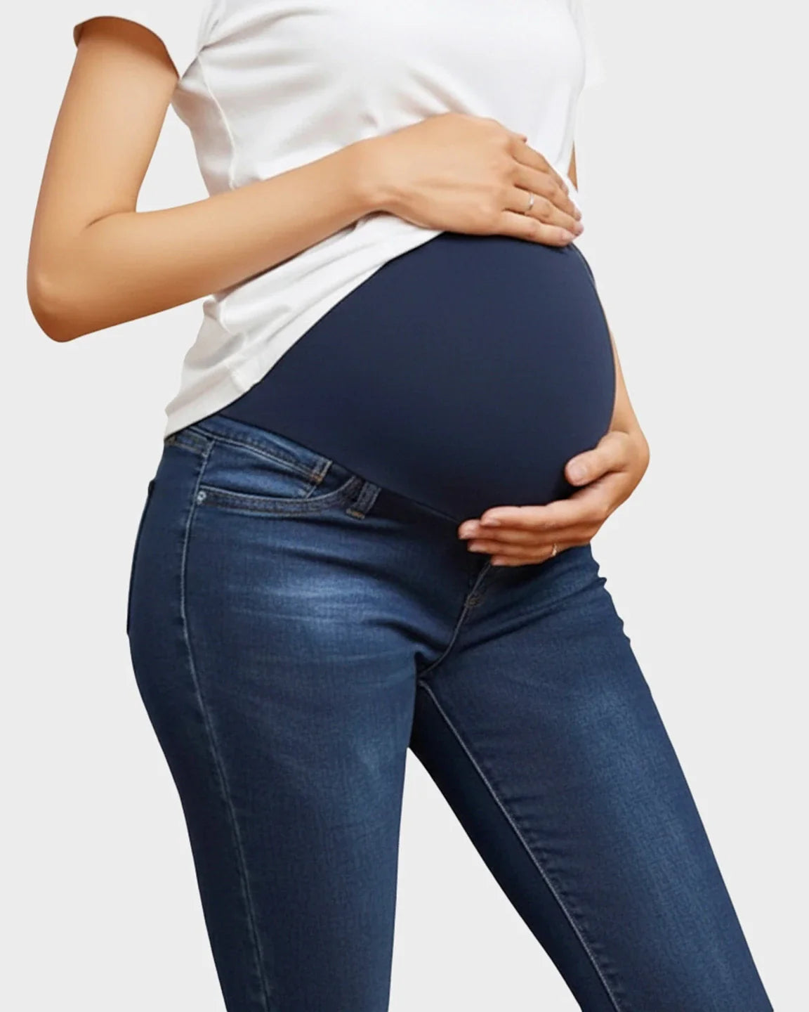 Woman wearing dark wash skinny maternity jeans with a navy high-waist elastic panel, supporting her baby bump.
