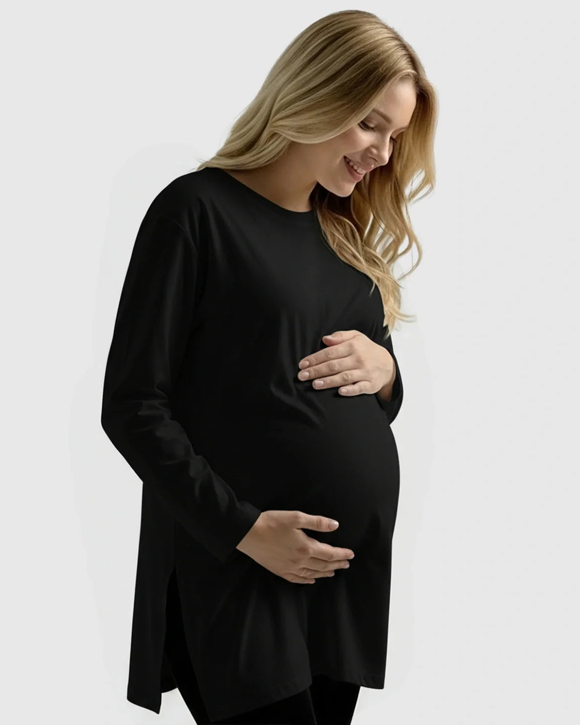 Smiling pregnant woman in a black long-sleeve cotton maternity top with side slits.