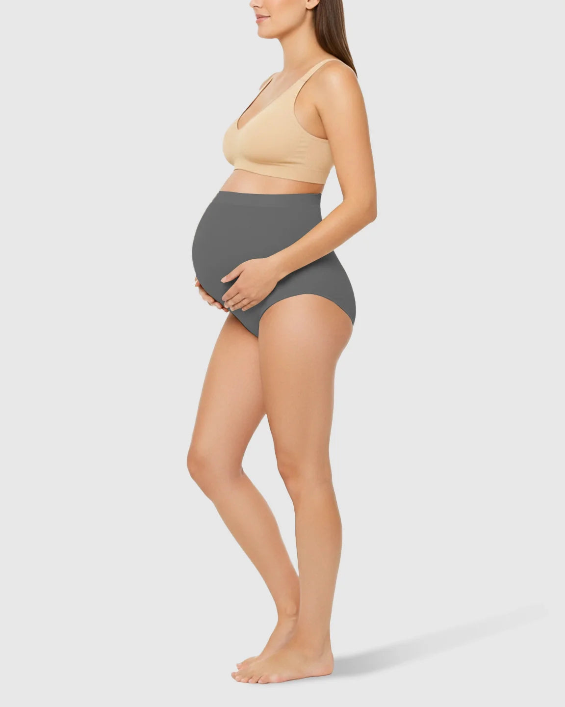 Pregnant woman in gray high-waist seamless belly-support maternity underwear, side view.