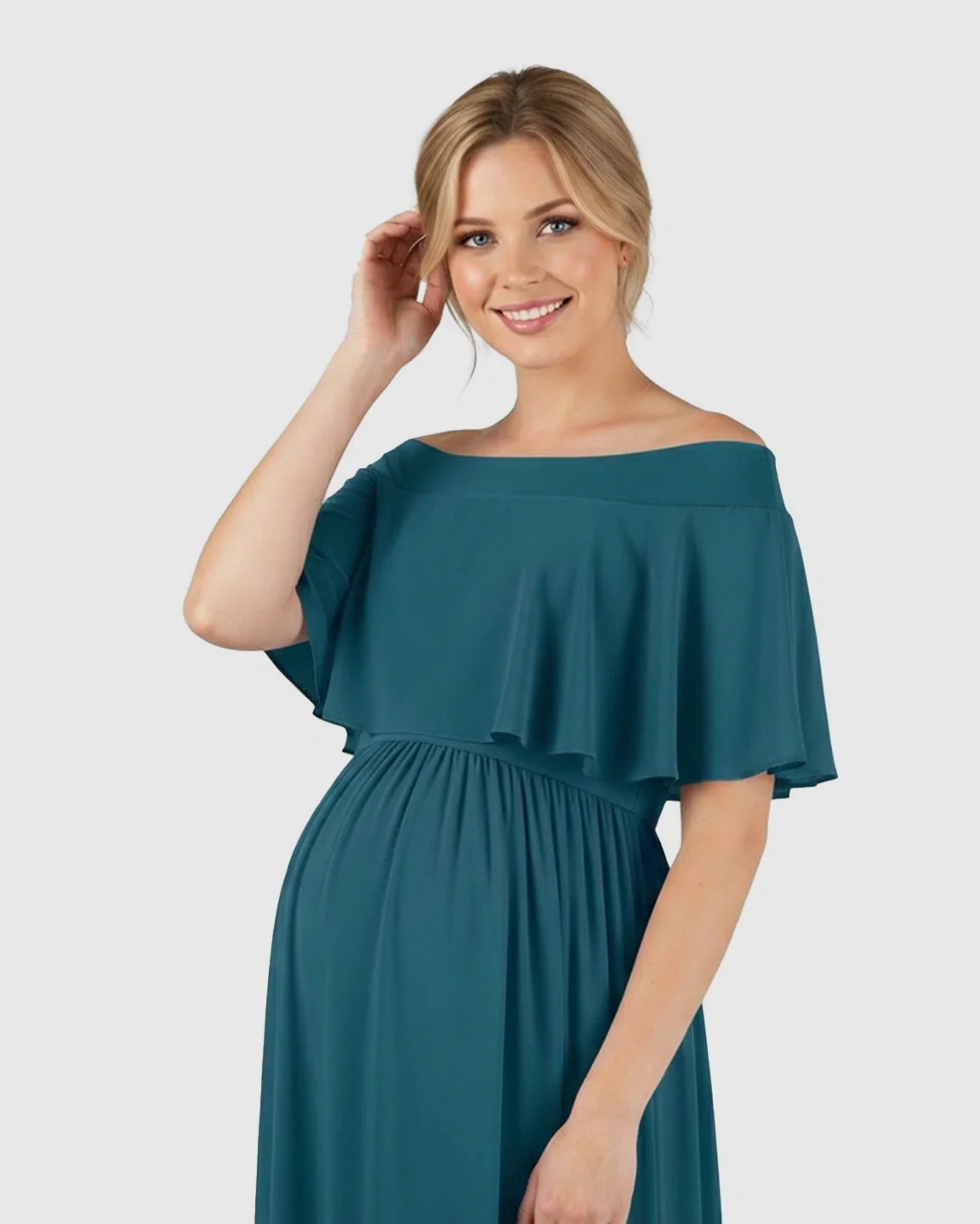 Smiling pregnant woman in a teal off-shoulder chiffon maternity photoshoot dress with a flowy silhouette.