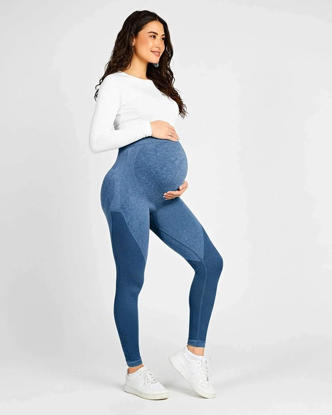 Smiling pregnant woman wearing blue high-elastic, body-hugging maternity leggings with textured panels.