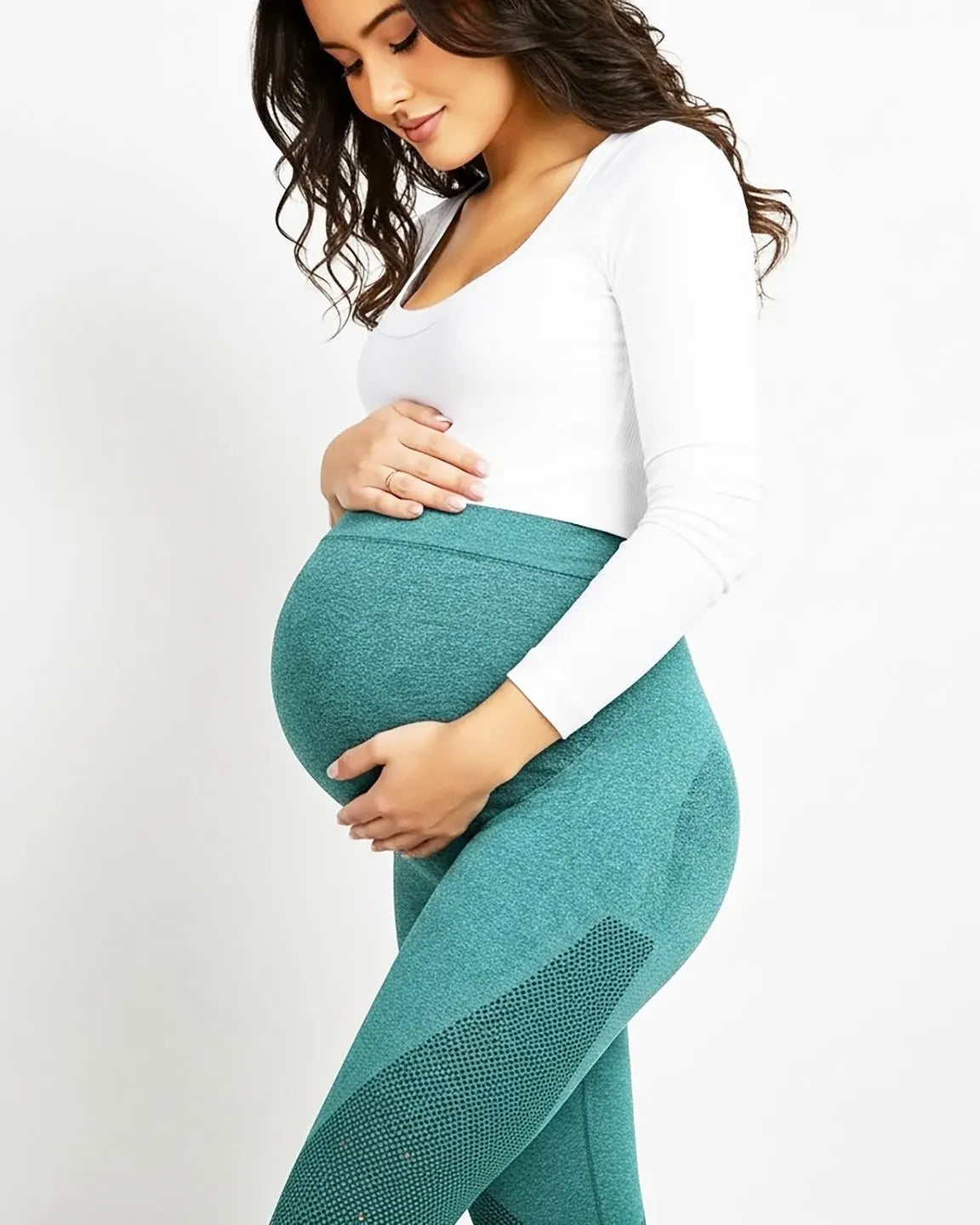 Pregnant woman in teal high-elastic body-hugging maternity leggings with subtle mesh details, cradling her bump.
