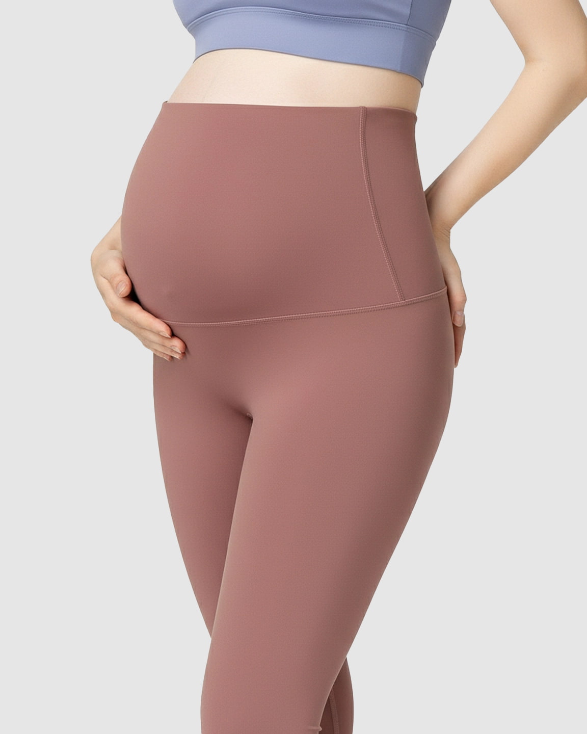 Pregnant woman wearing high-waist, soft stretch dusty rose maternity leggings with bump support.