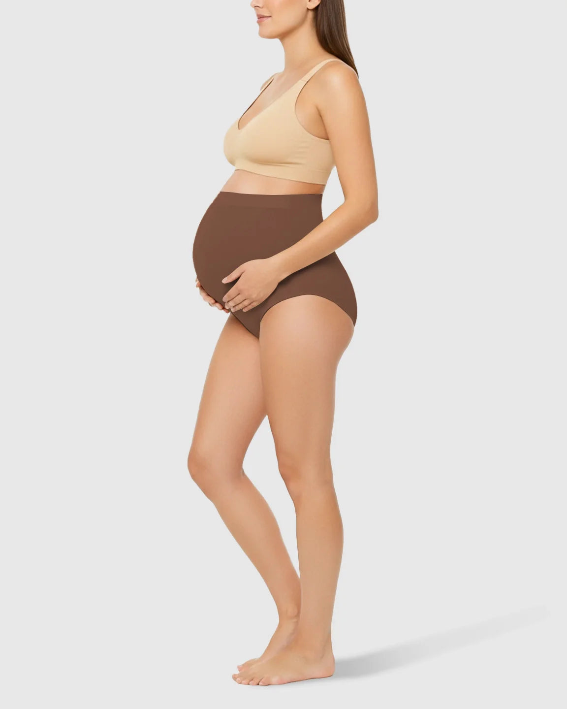 Pregnant woman in brown high-waist seamless belly-support maternity underwear and a beige bra.