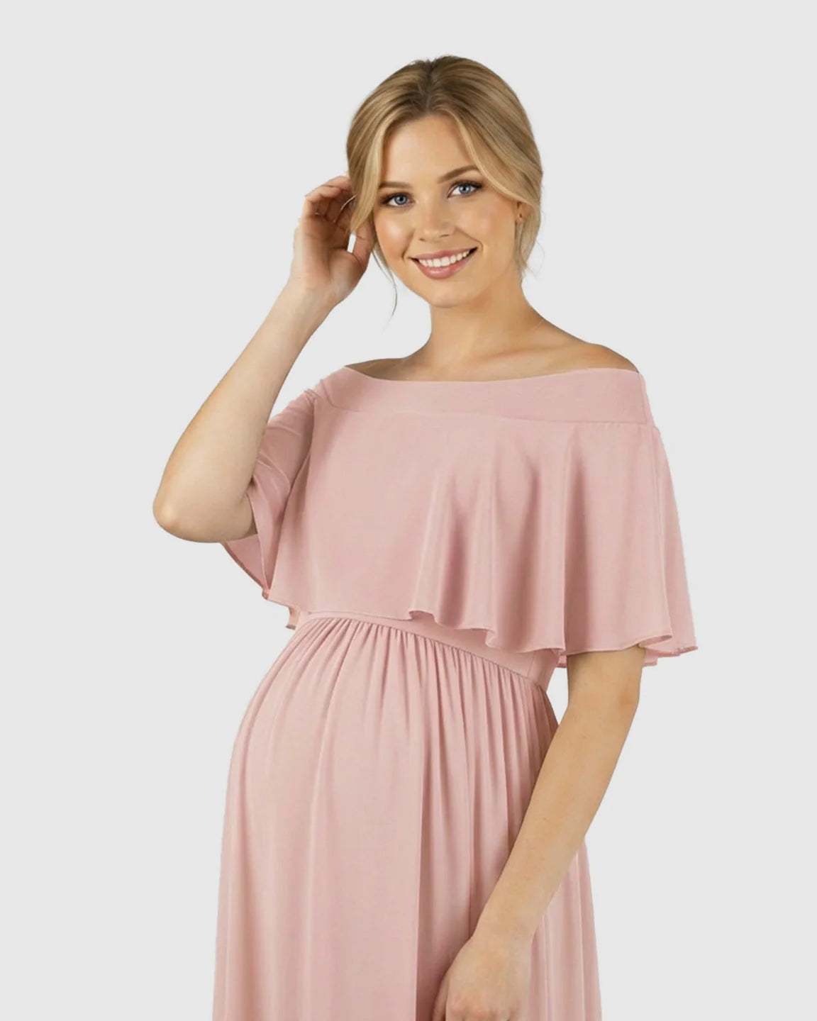 Blonde pregnant woman in a pink off-shoulder chiffon maternity photoshoot dress with a flowy silhouette.