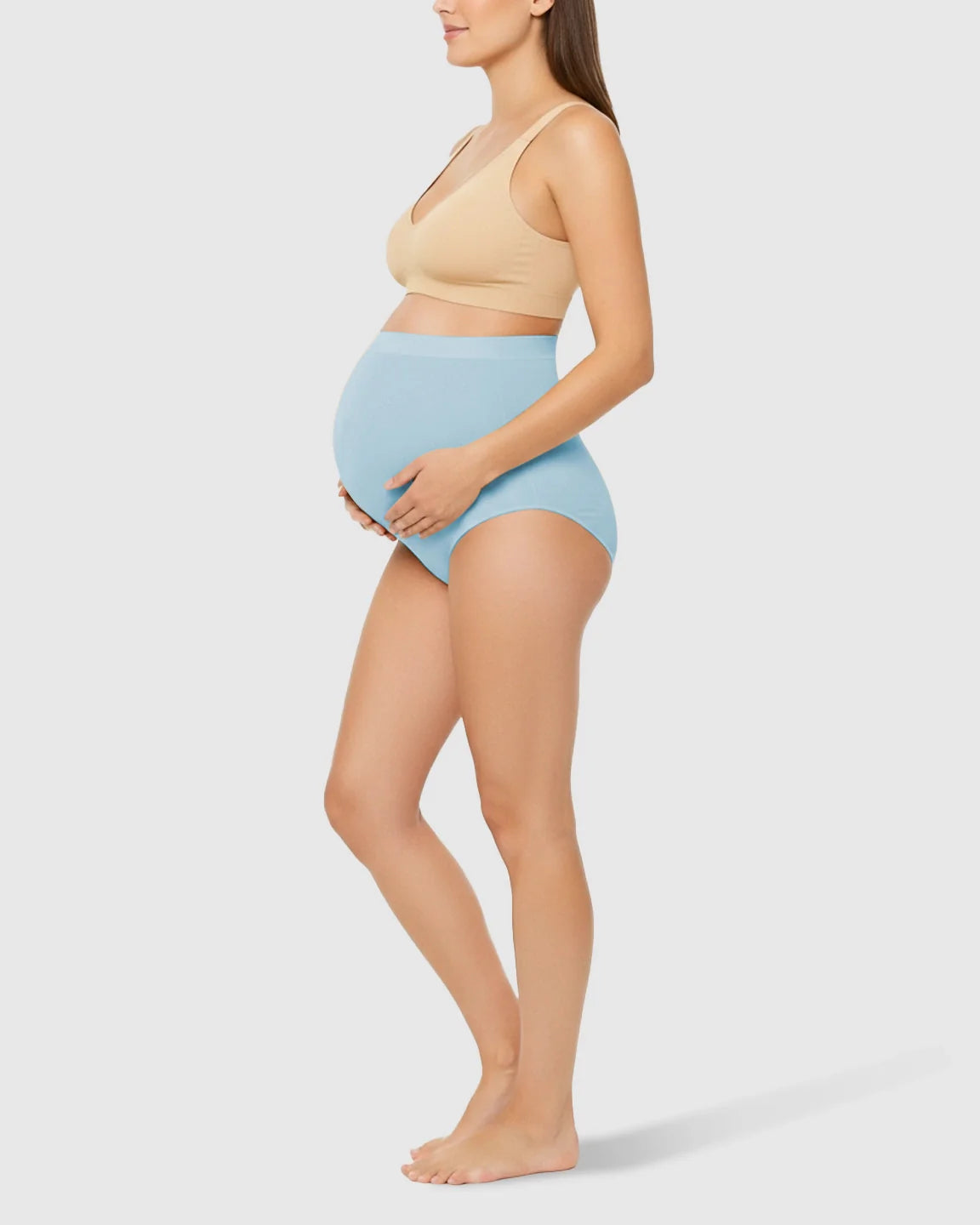 Pregnant woman in light blue high-waist seamless belly-support maternity underwear and a nude bra.