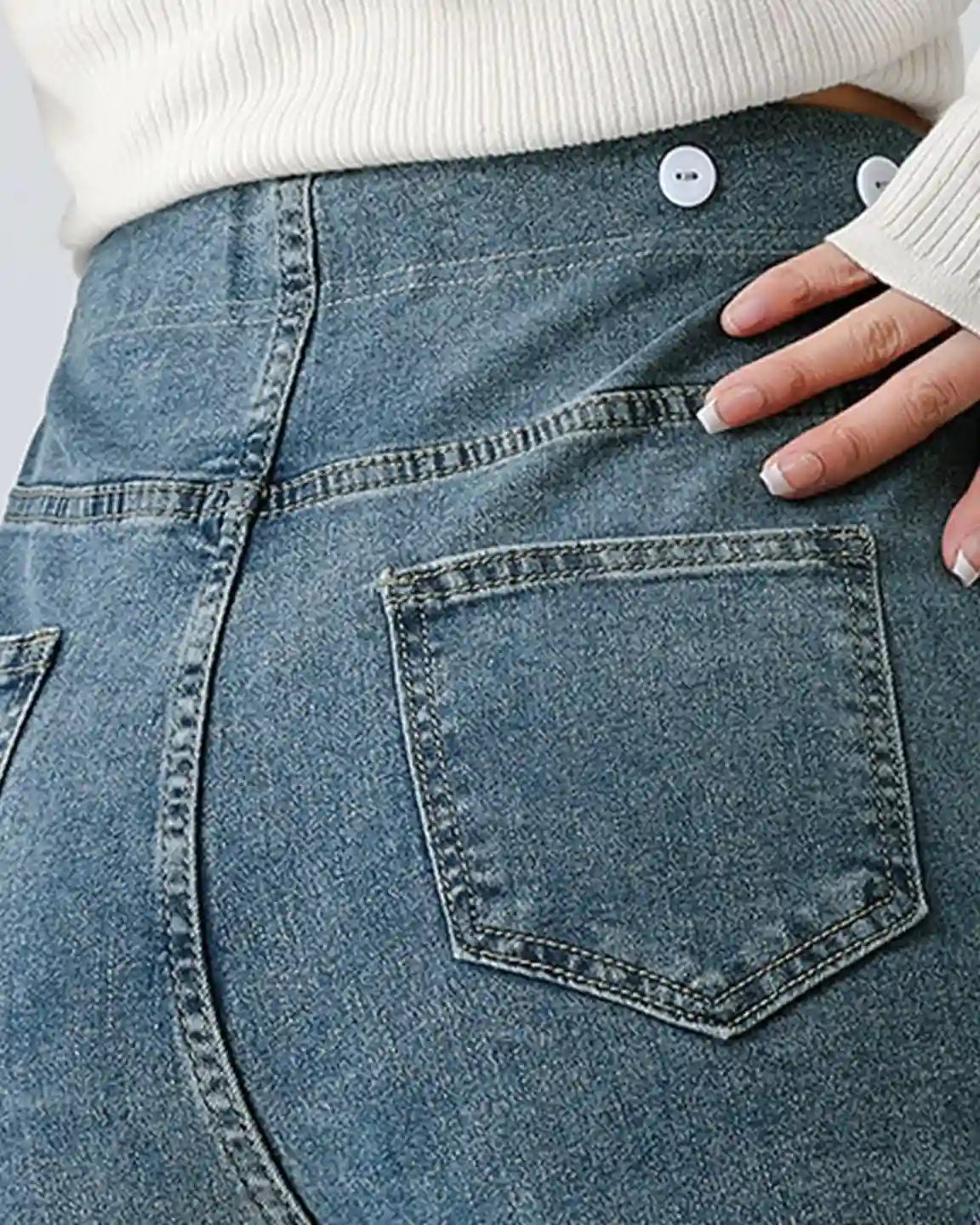 Close-up of a woman's back wearing blue stretch denim straight-leg maternity jeans with back pockets and white buttons.