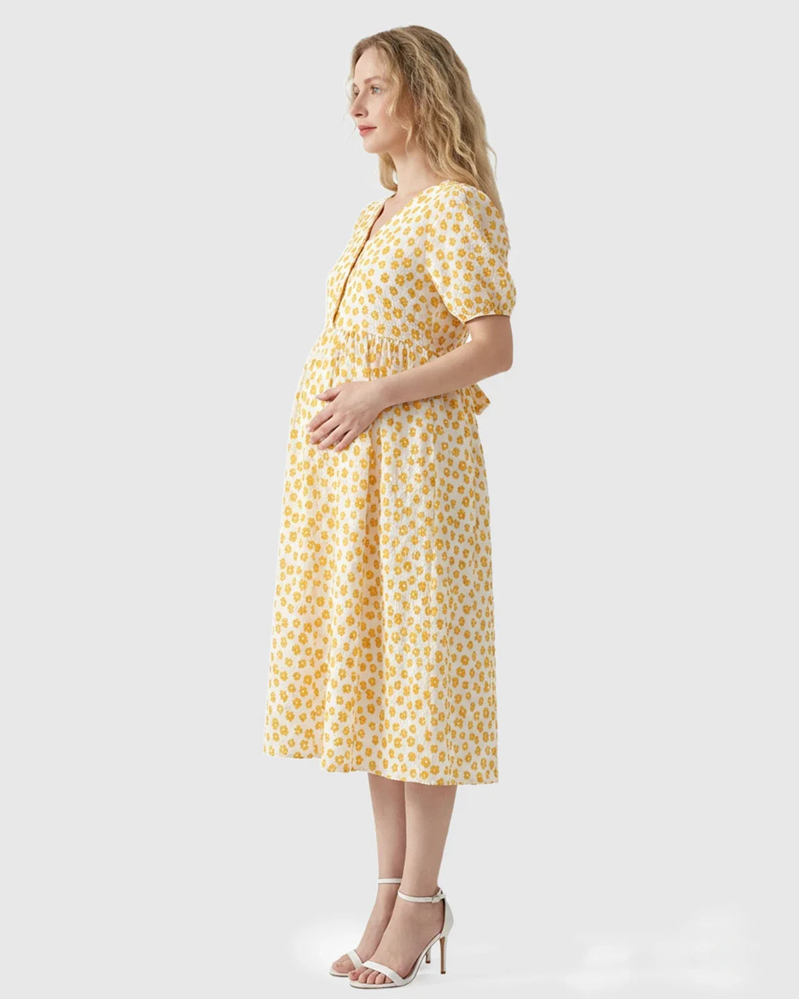 Woman in a yellow floral print maternity nursing midi dress with a V-neck and button-front.