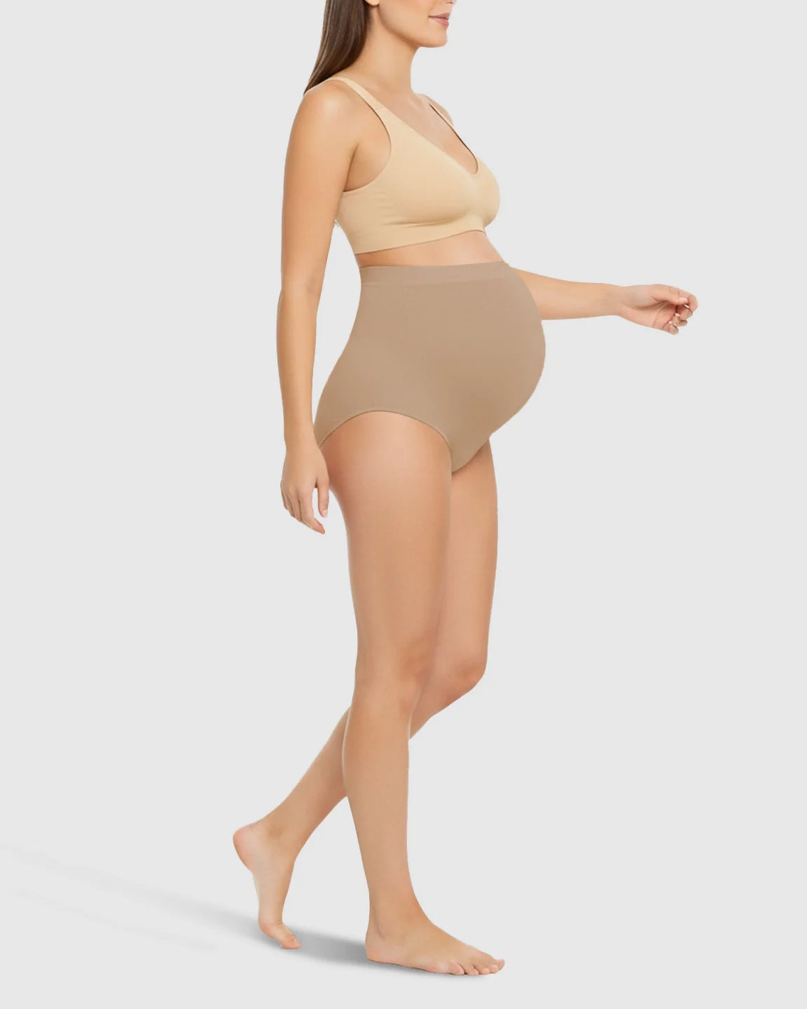 Pregnant woman wearing seamless, high-waist nude maternity underwear and matching bra, offering belly support.