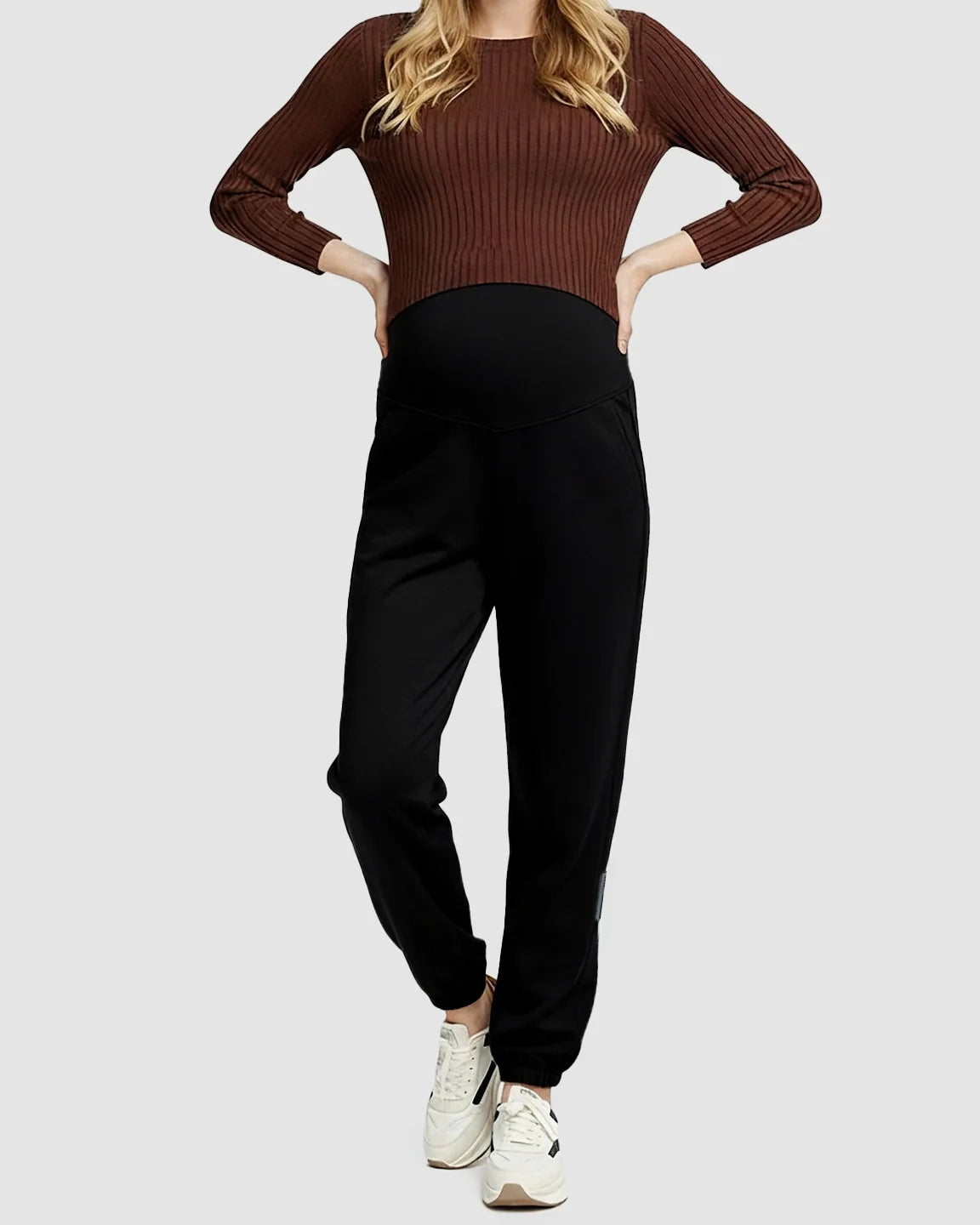 Woman wearing black soft knit maternity joggers with a supportive waistband and side pockets.
