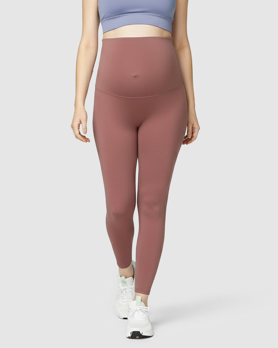 Woman wearing high-waist, soft stretch rose-colored maternity leggings with a supportive bump panel.