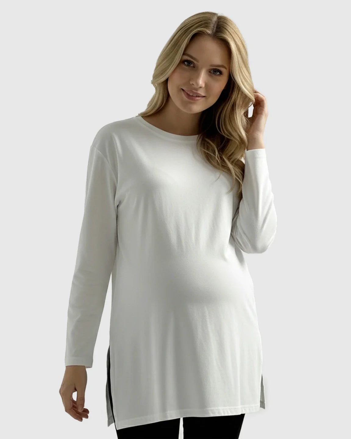 Blonde woman models a white, long-sleeve, relaxed-fit cotton maternity top with side slits.