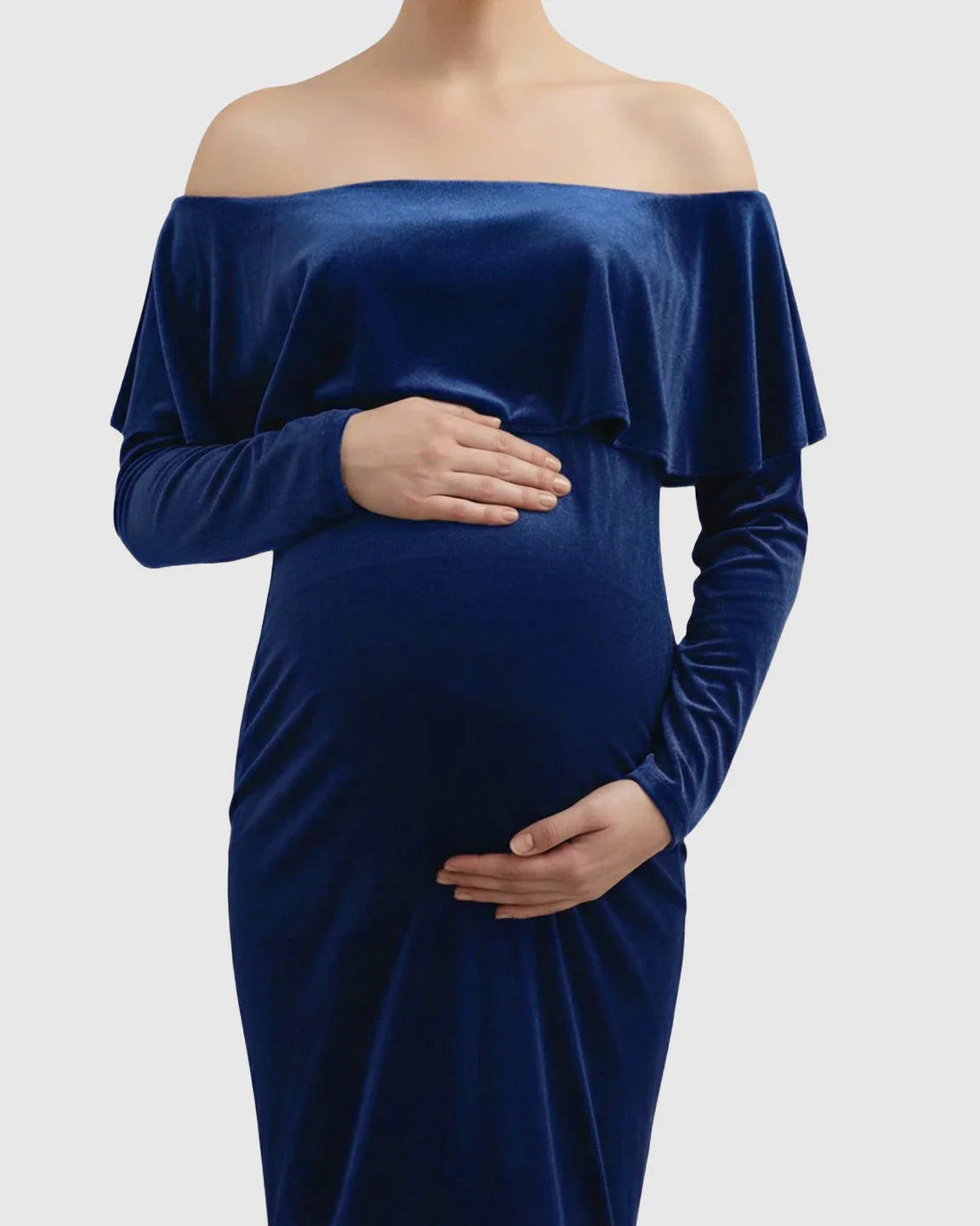 Navy blue velvet off-shoulder maternity photoshoot gown with long sleeves, highlighting a pregnant belly.