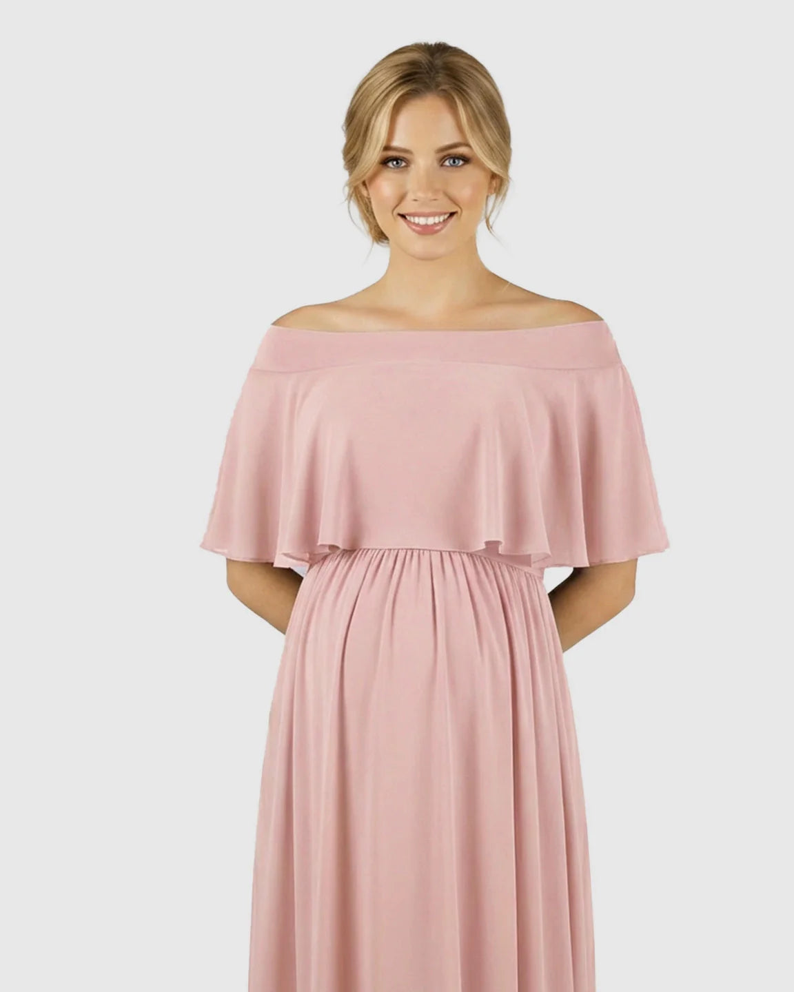 Smiling pregnant woman in a blush pink off-shoulder maternity dress with a flowy chiffon top.