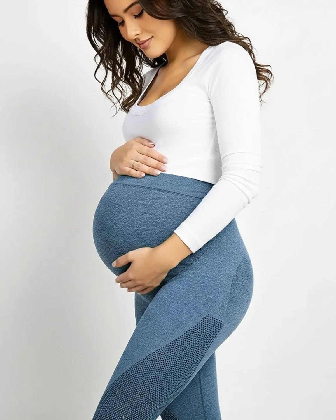 Pregnant woman in blue high-elastic body-hugging maternity leggings with a supportive belly panel and mesh details.